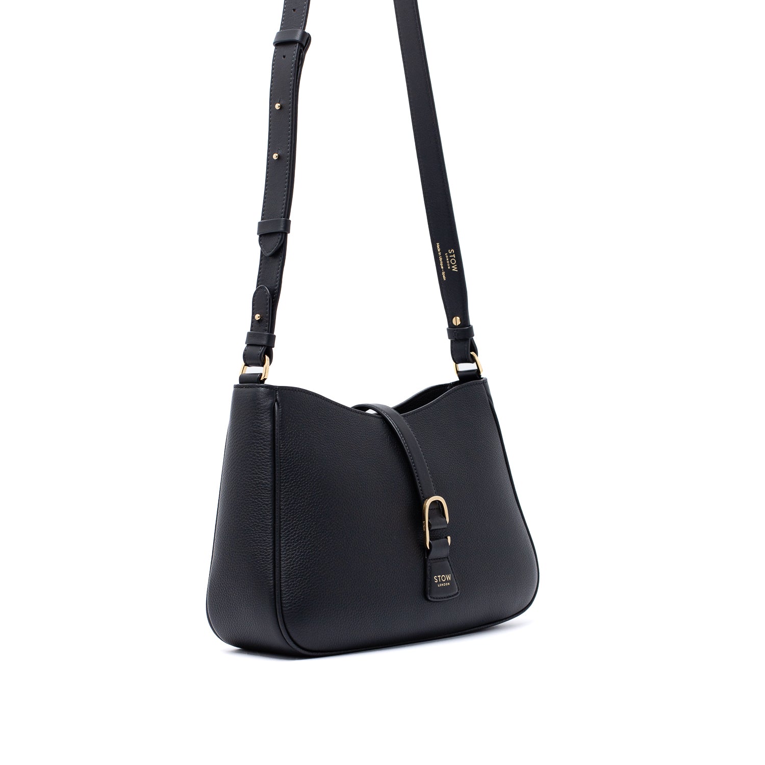 Off-axis view of STOW London's Beth bag and detachable crossbody strap in Black leather featuring gold stainless steel hardware on a white background