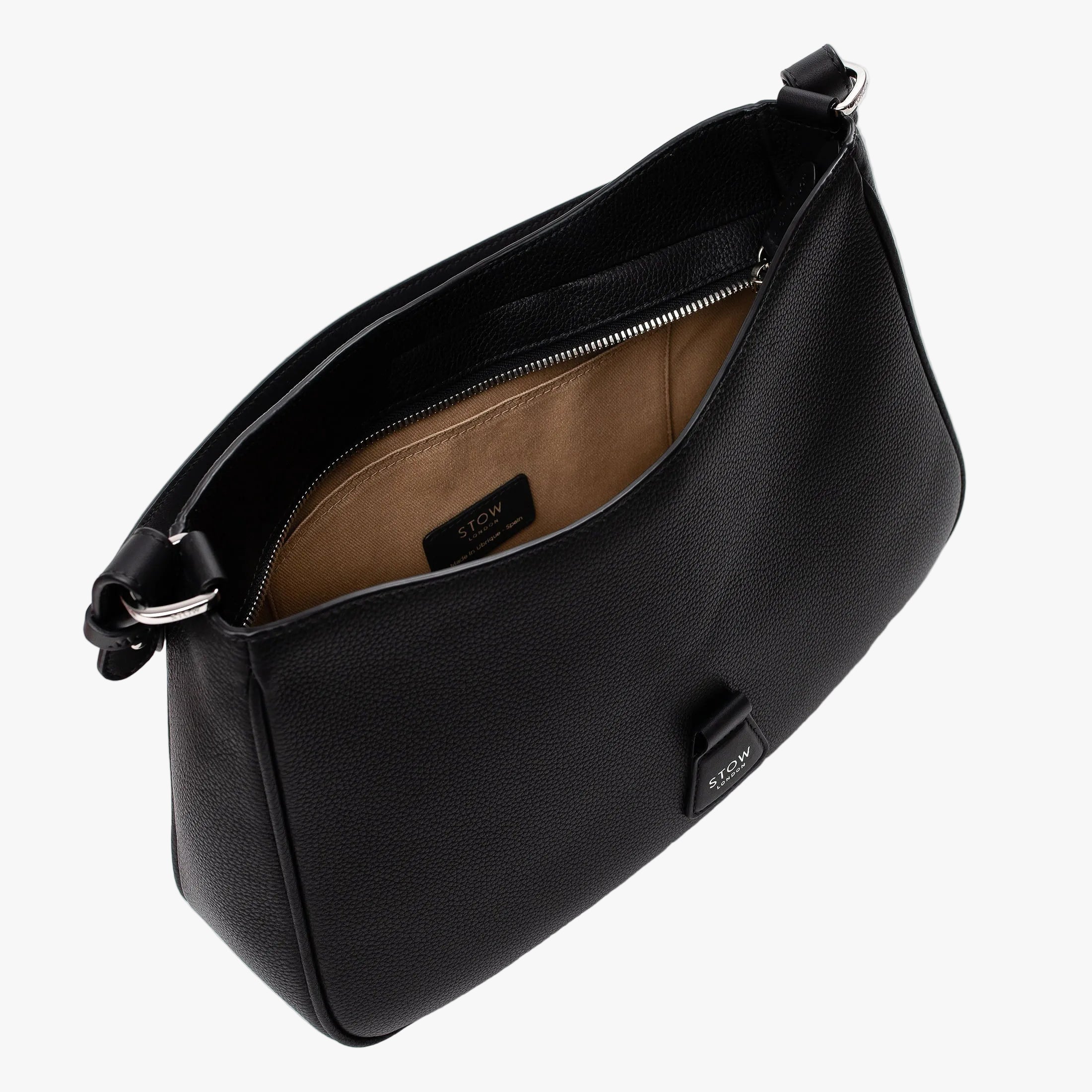 Top angled view of STOW London's Beth bag in Black pebbled and smooth leather with zipper open showing the interior cotton lining and card holder pocket, featuring silver stainless steel hardware on a white background