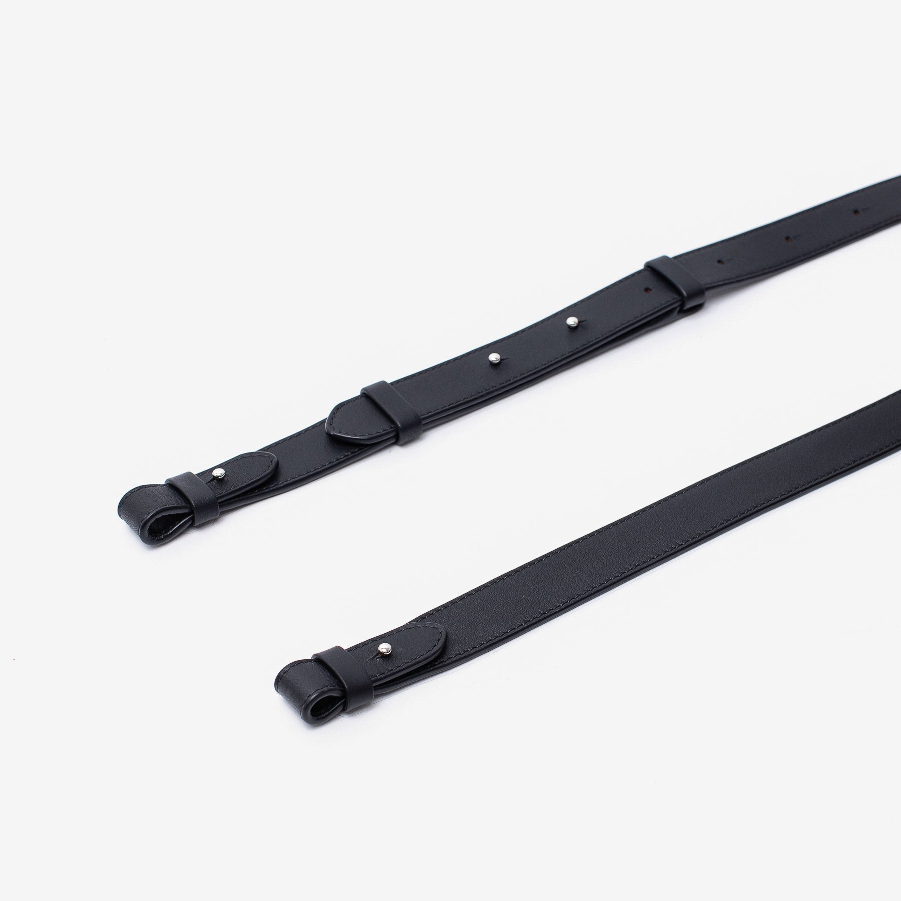 Close up shot of STOW London's detachable crossbody strap for the Beth bag in Black leather featuring silver stainless steel hardware on a white background