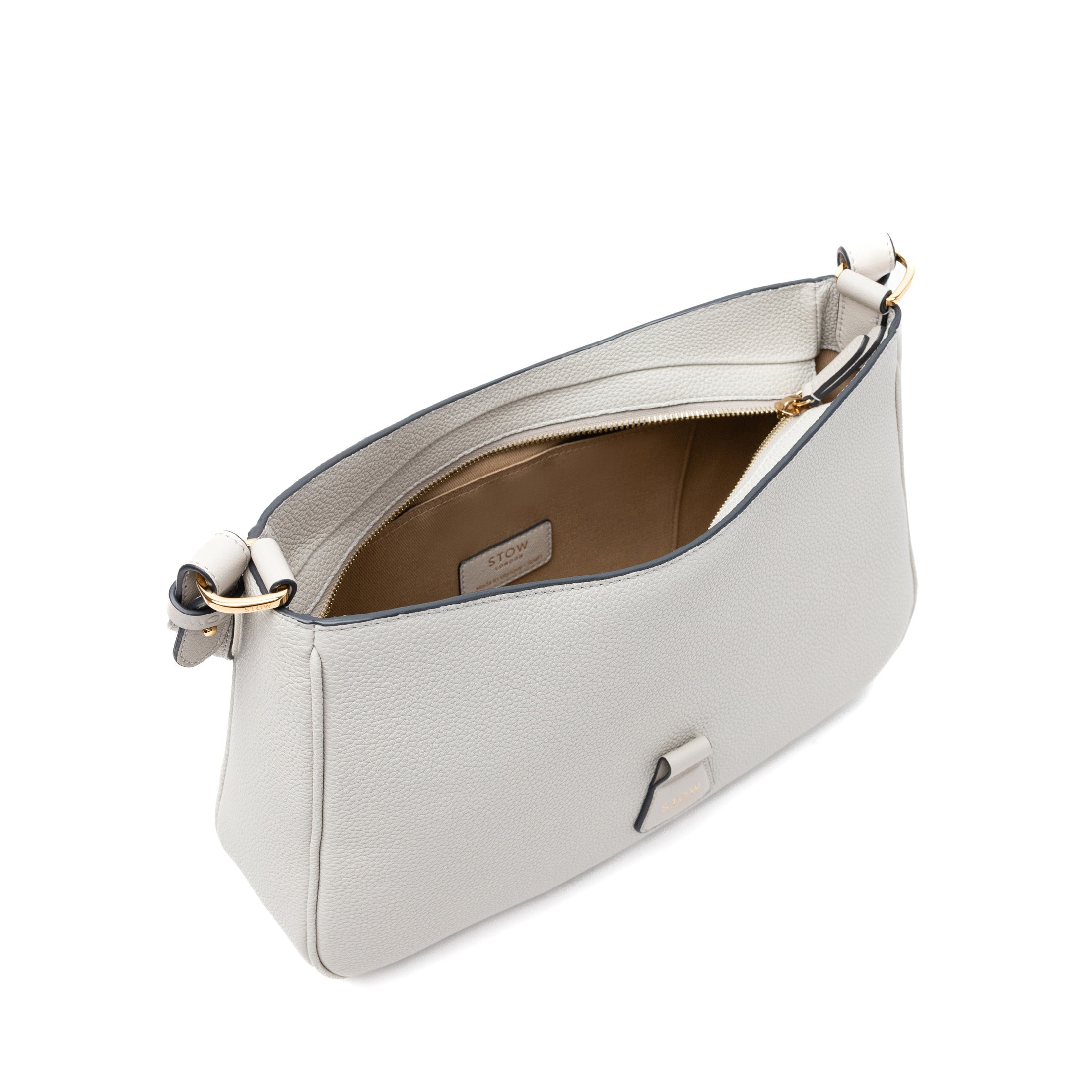 Top angled view of STOW London's Beth bag in Cloud Grey pebbled and smooth leather with zipper open showing the interior cotton lining and card holder pocket featuring gold-coated stainless steel hardware on a white background