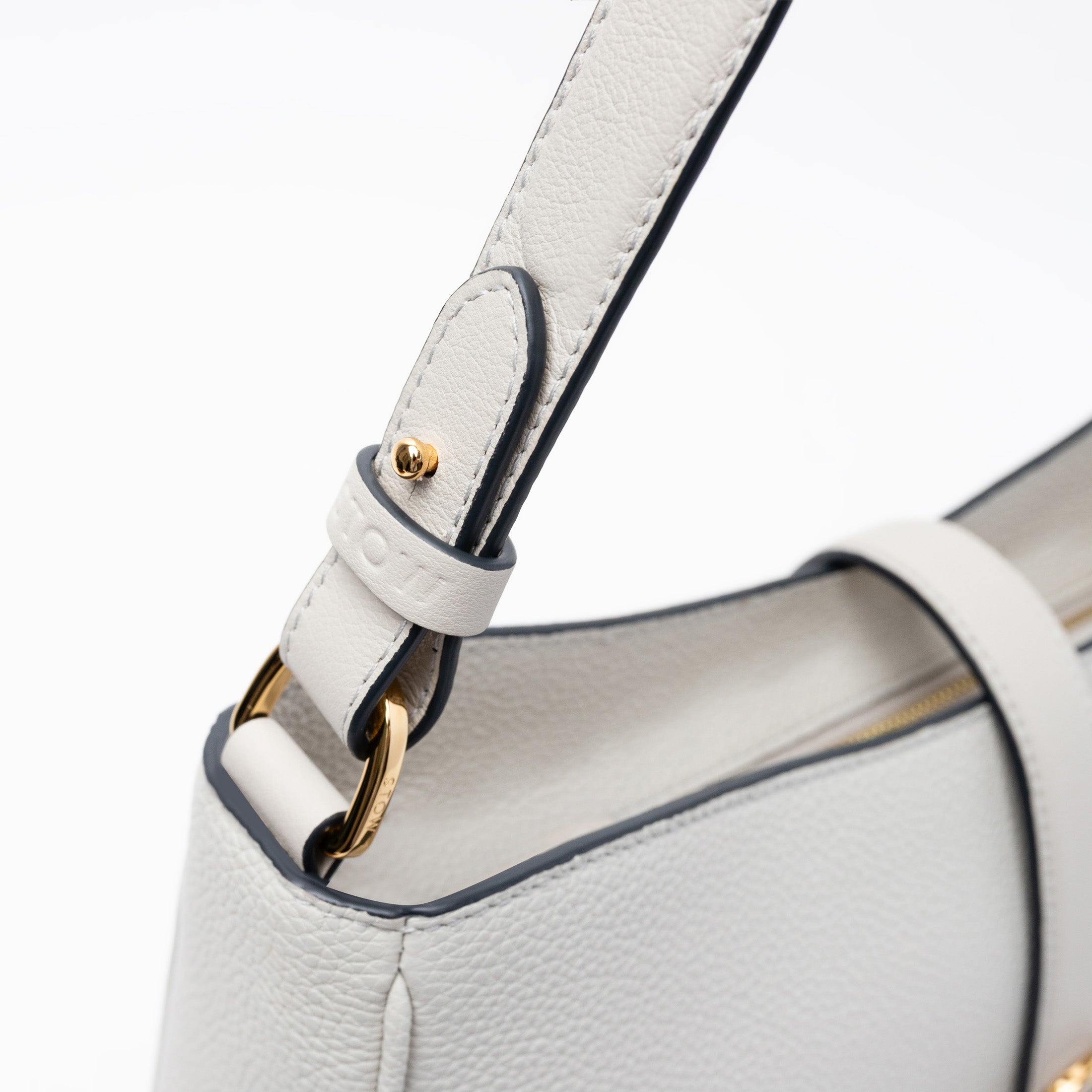 Close up view of STOW London's Beth bag in Cloud Grey pebbled and smooth leather featuring the detachable strap and gold-coated stainless steel hardware on a white background