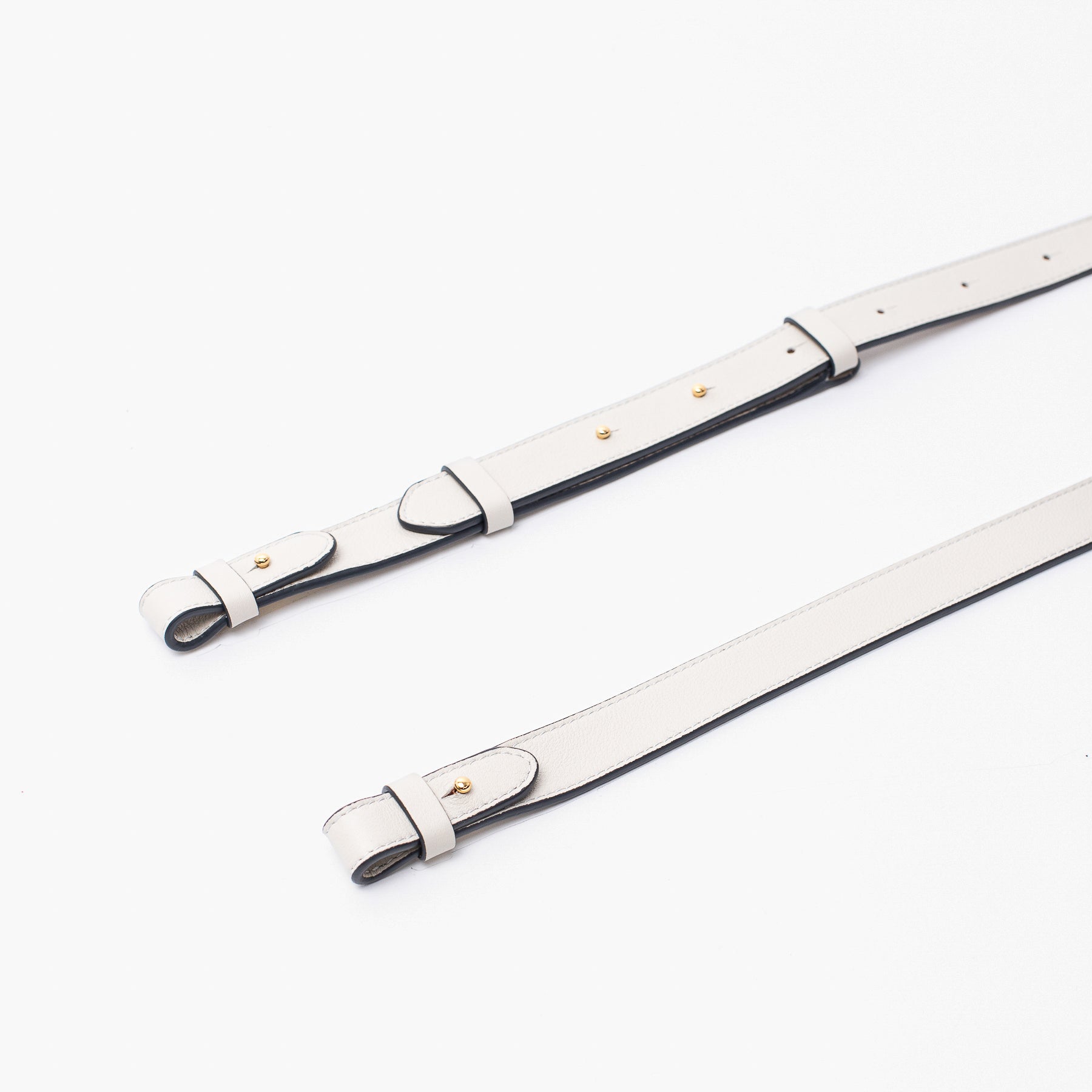 Close up of STOW London's detachable crossbody strap for the Beth bag in Cloud Grey leather featuring gold stainless steel hardware on a white background