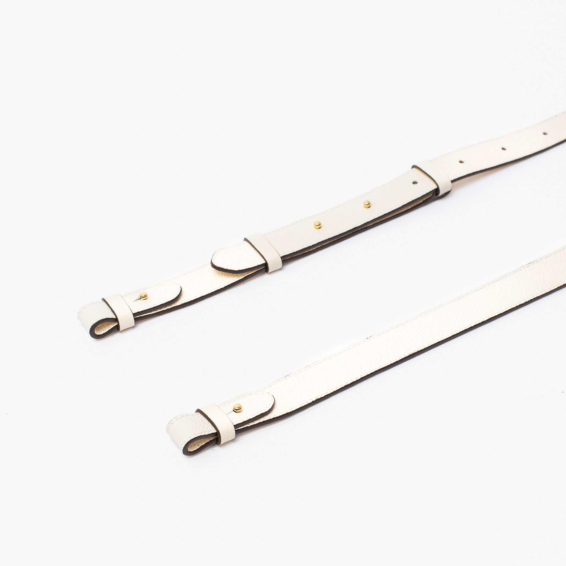 Close up shot of STOW London's detachable crossbody strap for the Beth bag in Spring Moon leather featuring Gold stainless steel hardware on a white background