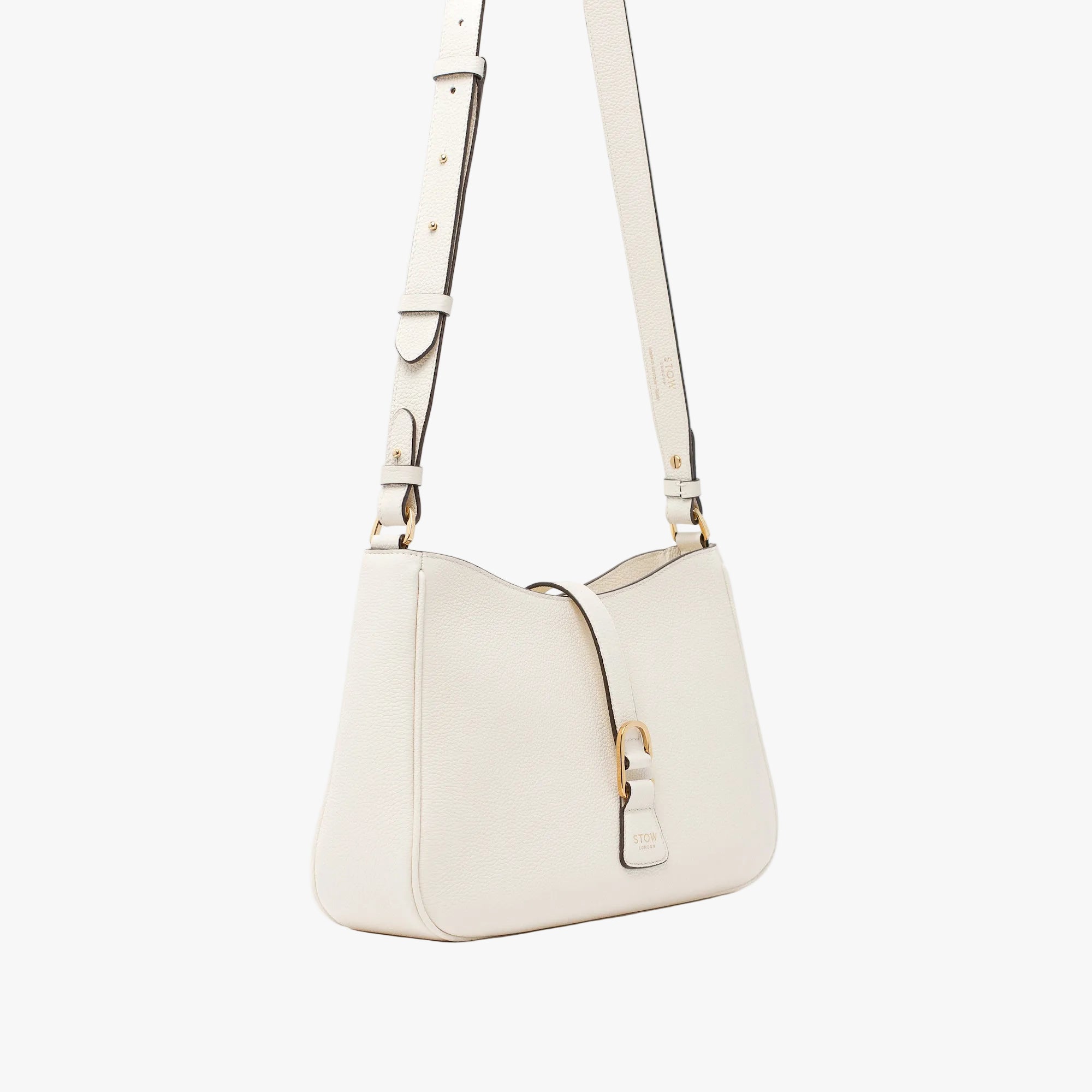 Off-axis view of STOW London's Beth bag and detachable crossbody strap in Spring Moon leather featuring gold stainless steel hardware on a white background
