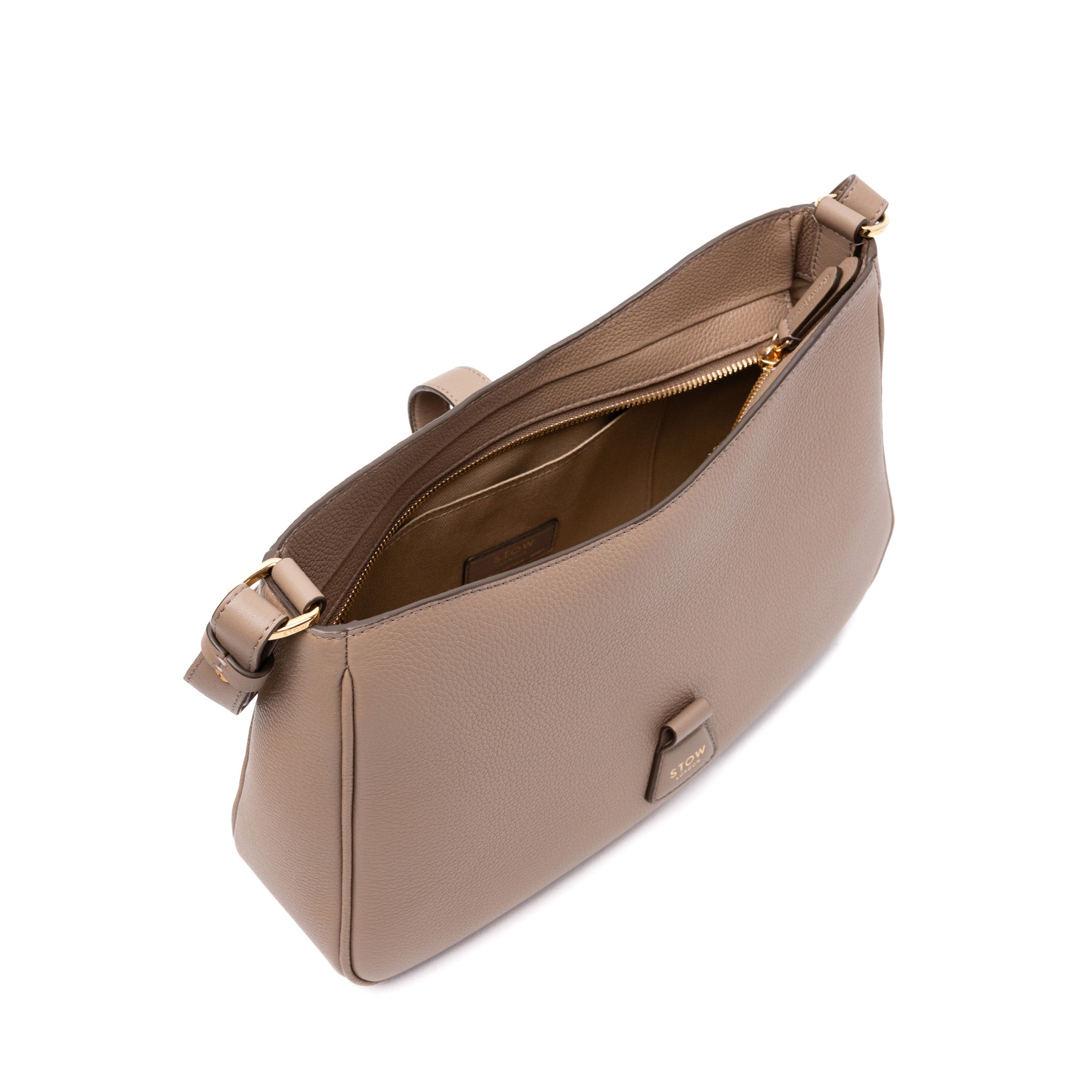 Top angled view of STOW London's Beth bag in Warm Taupe pebbled and smooth leather with zipper open showing interior cotton lining and card holder pocket featuring gold-coated stainless steel hardware on a white background