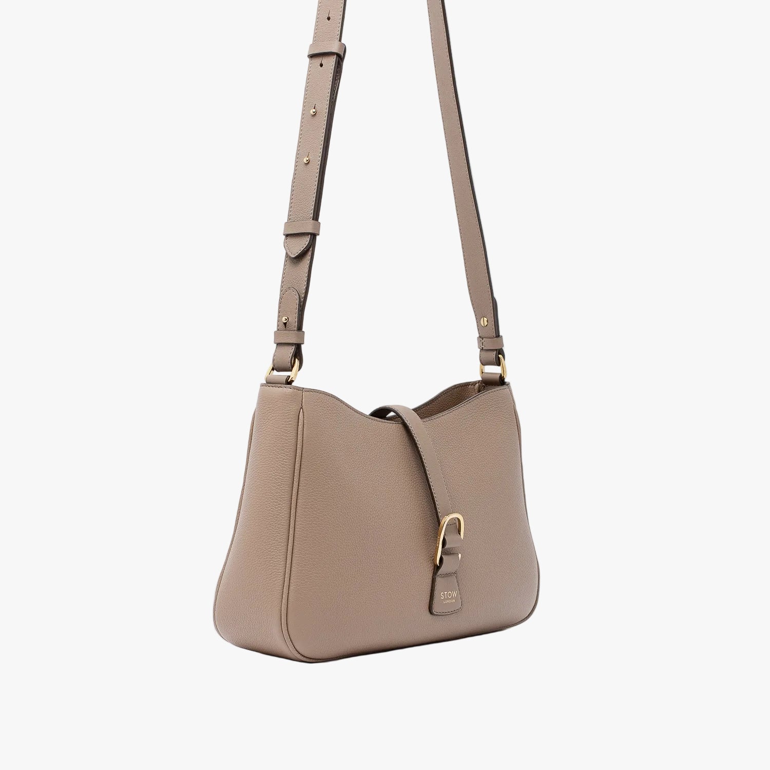 Off-axis view of STOW London's Beth bag and detachable crossbody strap in Warm Taupe leather featuring gold stainless steel hardware on a white background