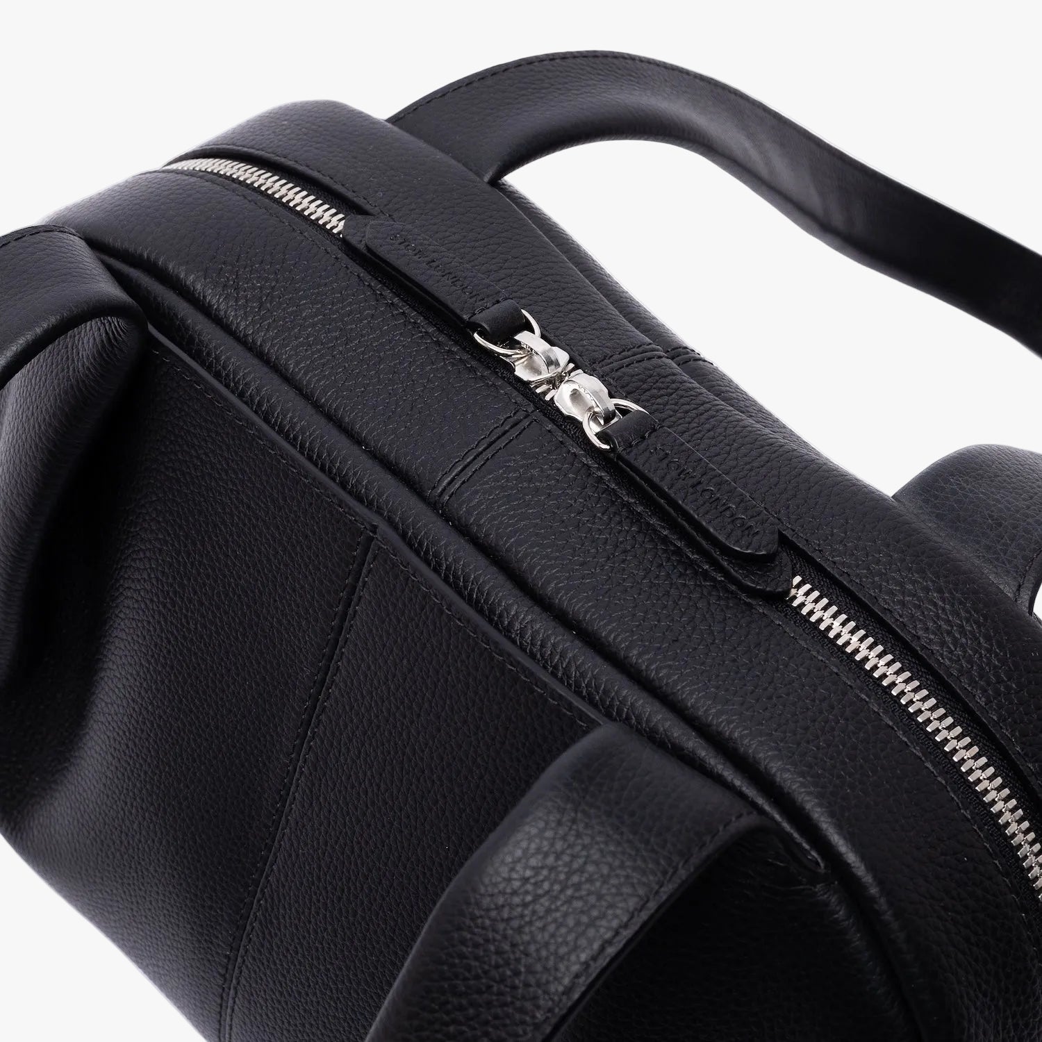 Close up of the silver zip top closure on STOW London's Bowling bag in Black pebbled leather on a light grey background