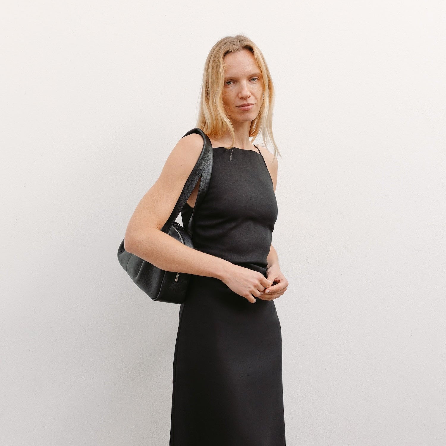 Model wearing STOW London's Bowling bag in Black pebbled leather featuring the pleated front panel and silver stainless steel hardware