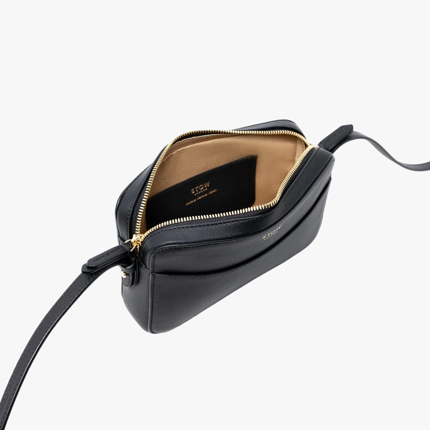 Top angled view of STOW London's Camera bag in Black Smooth leather with zipper open showing the interior card holder pocket featuring gold-coated stainless steel hardware on a white background