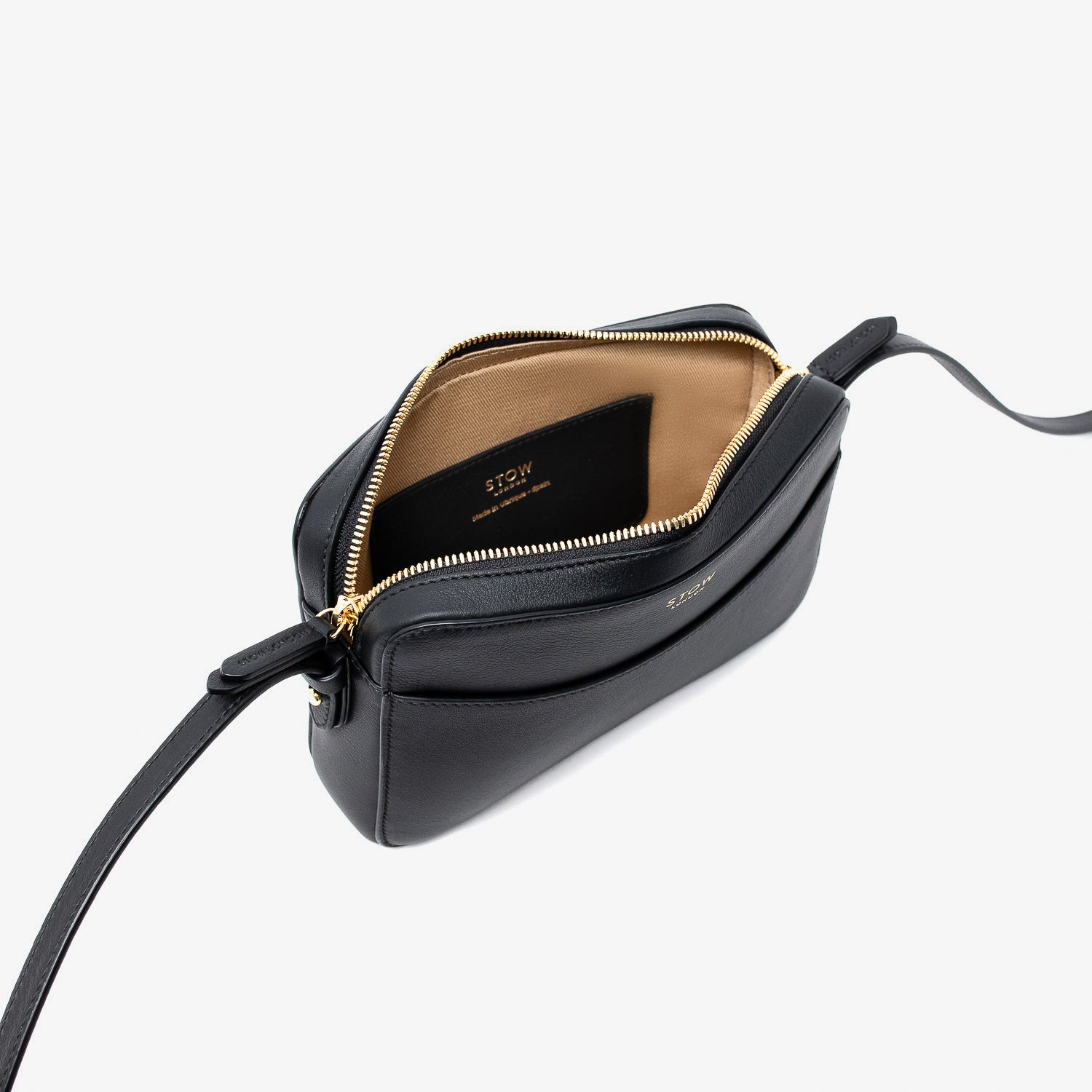 Top angled view of STOW London's Camera bag in Black Smooth leather with zipper open showing the interior card holder pocket featuring gold-coated stainless steel hardware on a white background