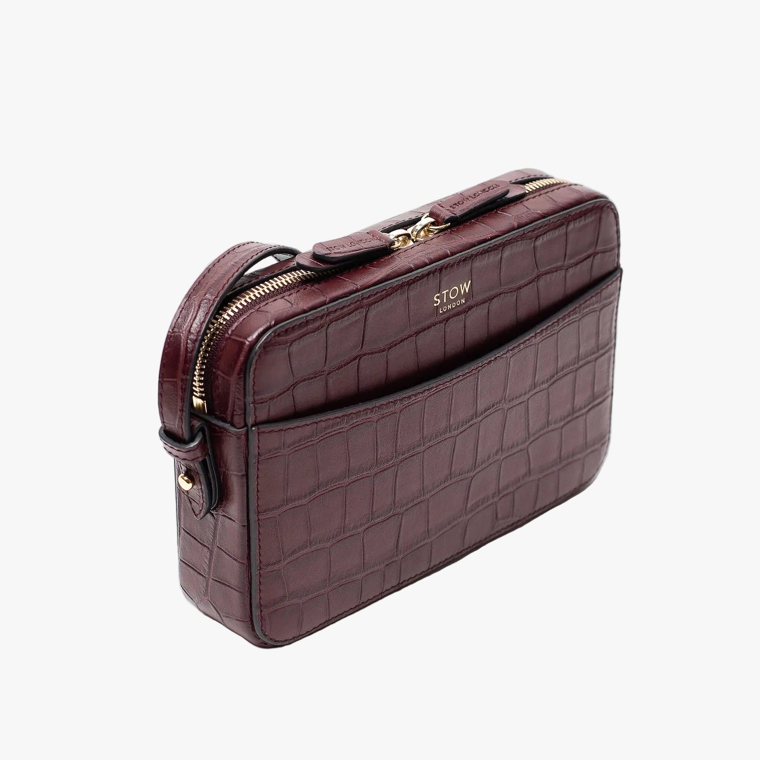 Off-axis view of STOW London's Camera bag in Burgundy Embossed Croc leather featuring gold-coated stainless steel hardware on a white background