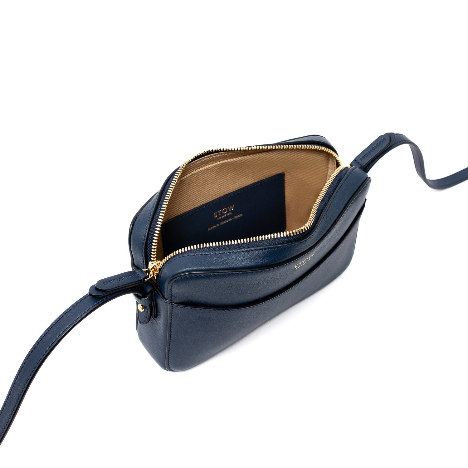 Top angled view of STOW London's Camera bag in Navy Smooth leather with zipper open showing the interior card holder pocket featuring gold-coated stainless steel hardware on a white background