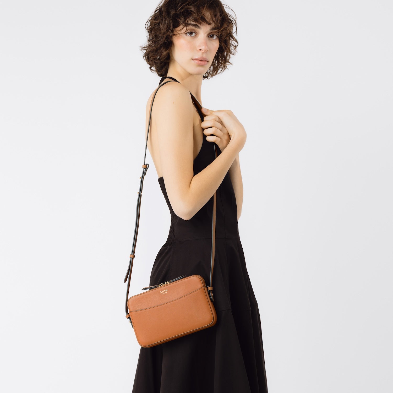 Model wearing STOW London's Camera bag in Earth Tan smooth leather on her shoulder featuring gold-coated stainless steel hardware