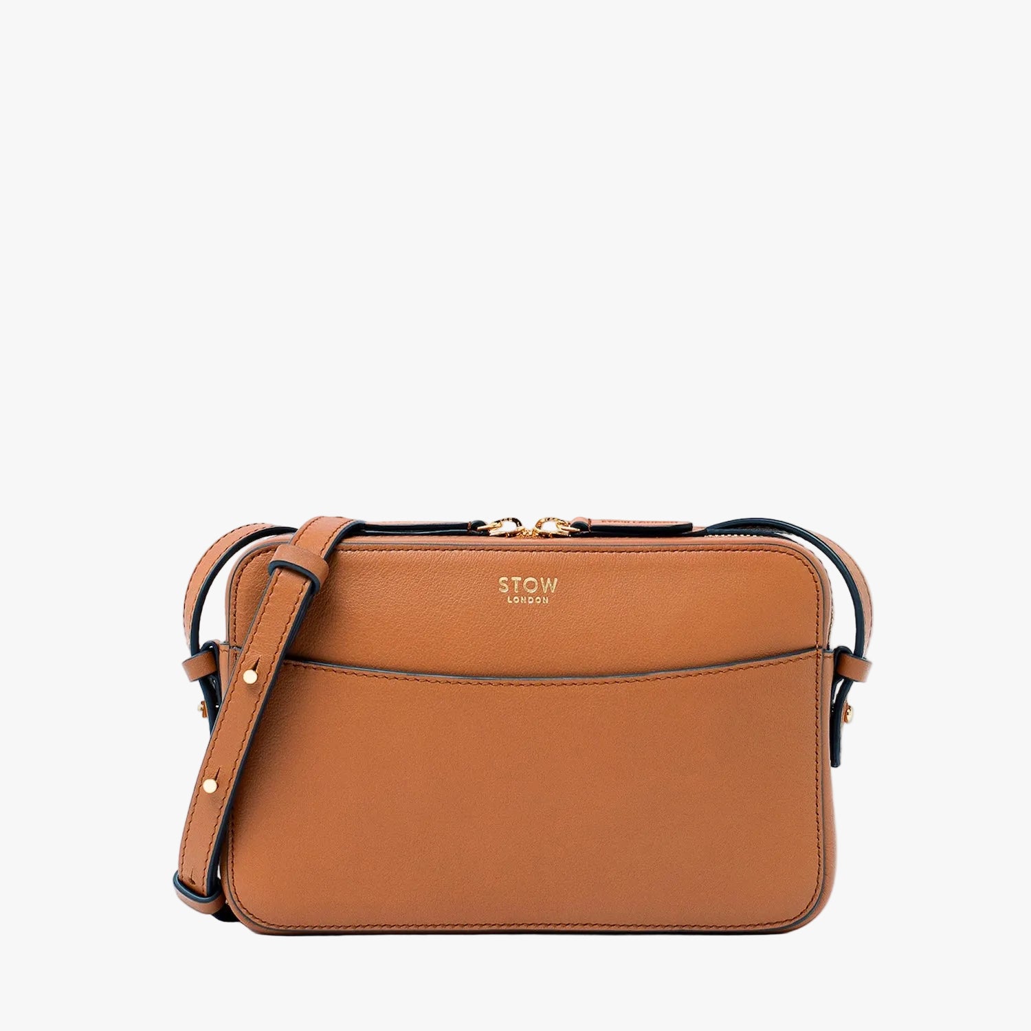 STOW London's Camera bag in Earth Tan pebbled leather featuring gold-coated stainless steel hardware on a light grey background