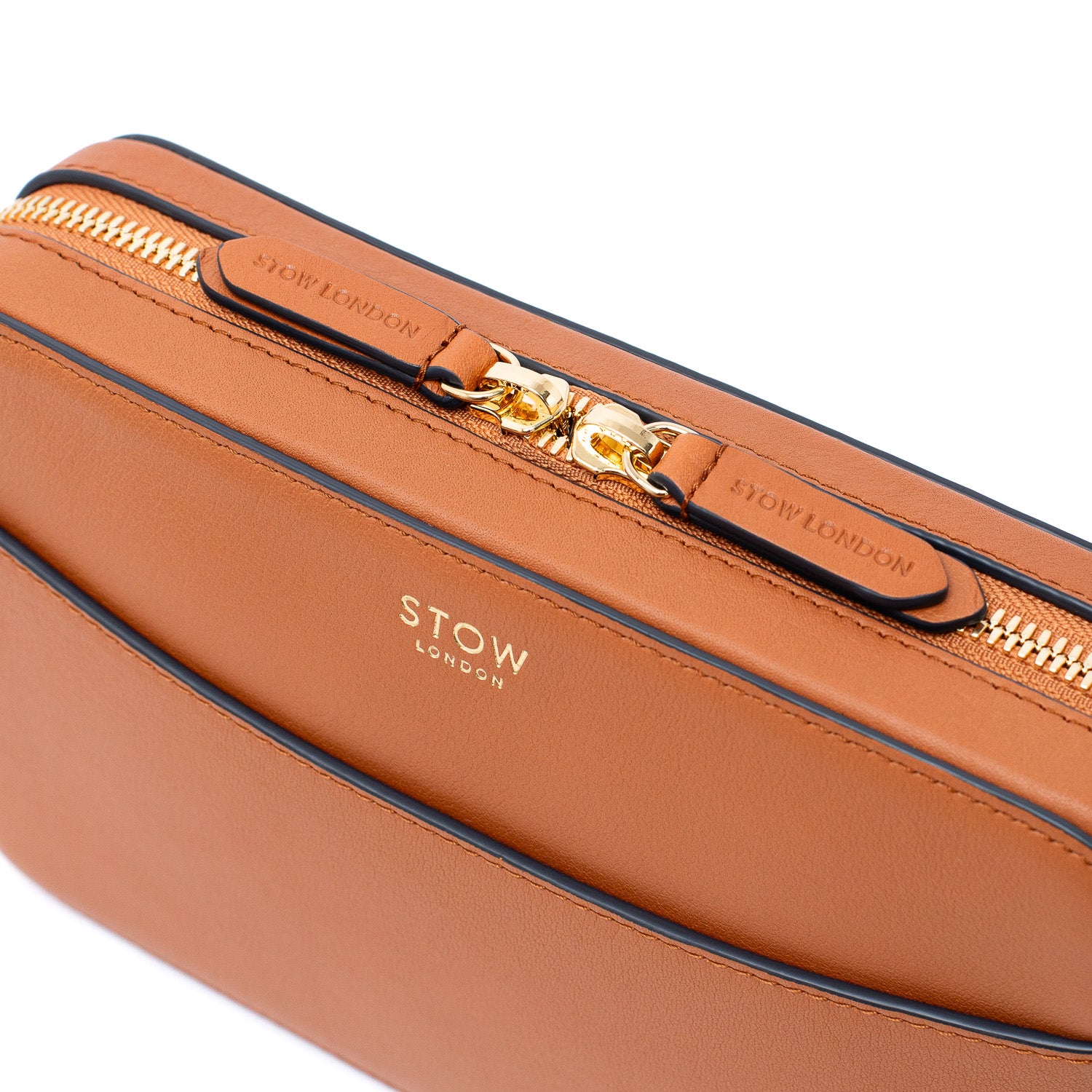 Close-up shot of STOW London's Camera bag in Earth Tan smooth leather featuring gold-coated zips and branding on a white background