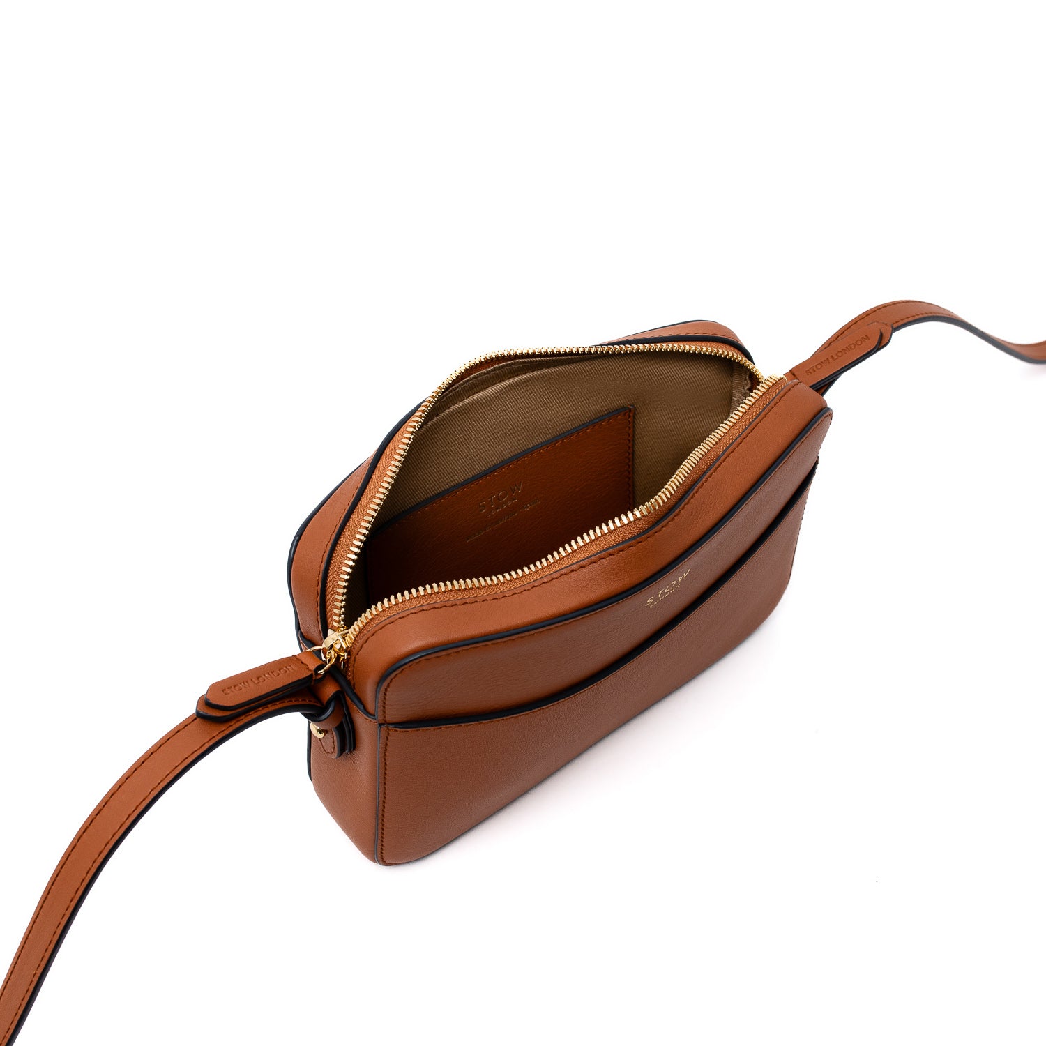 Elevated angle view of STOW London's Camera bag in Earth Tan smooth leather with zip open showing interior card pocket and cotton lining on a white background