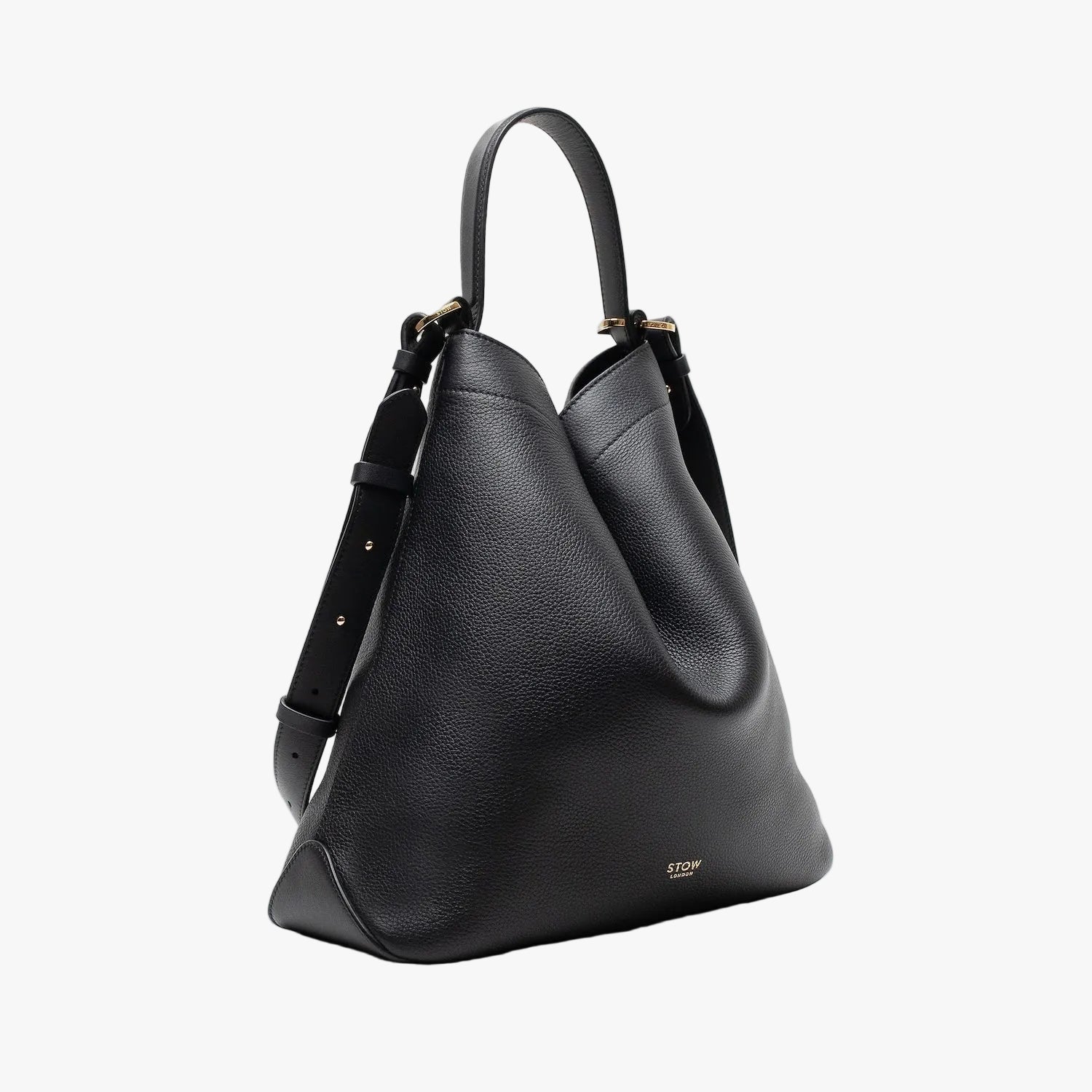 Off-axis shot of STOW London's Curve bag in Black pebbled leather in a triangular shape featuring gold-coated stainless steel hardware on a light grey background