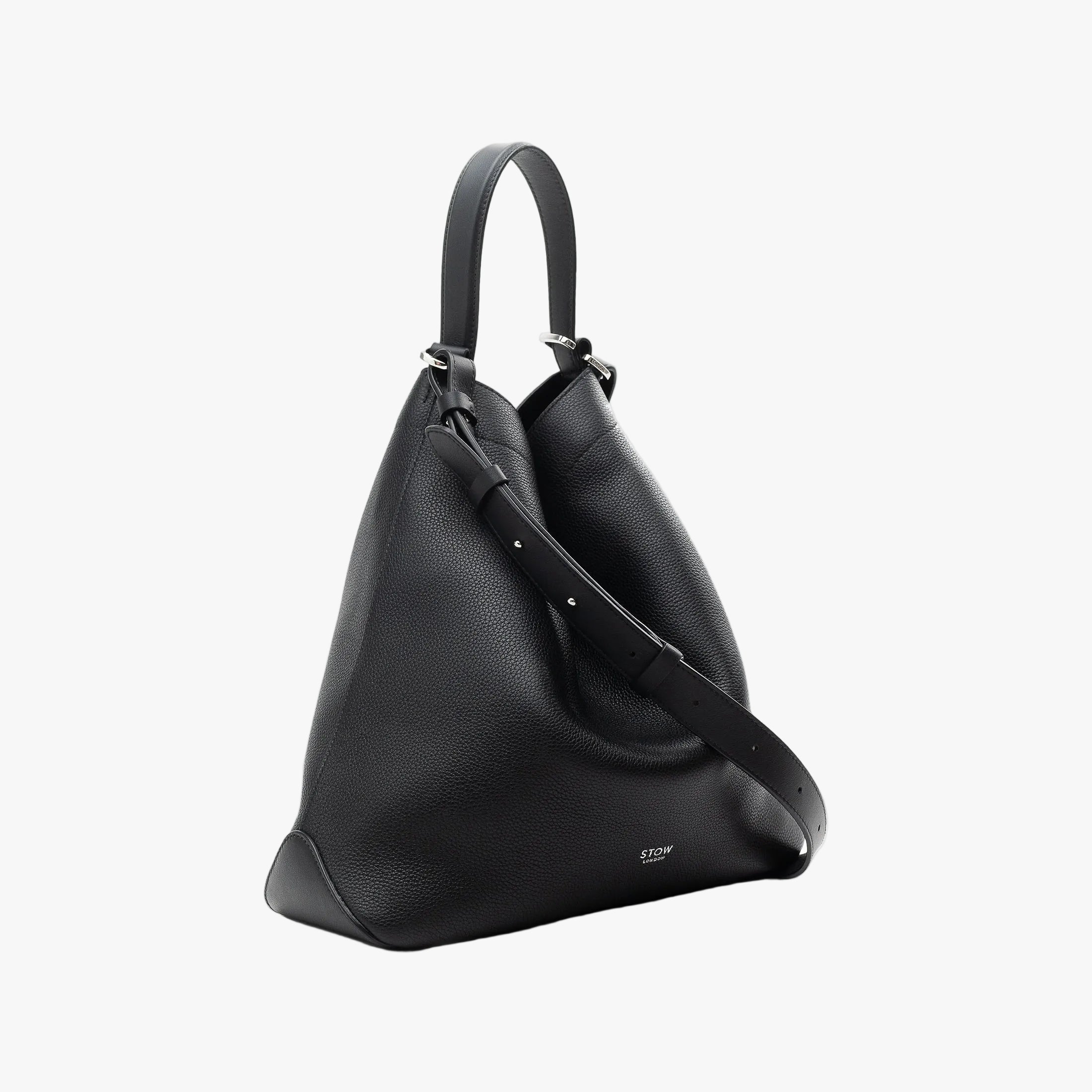 Off-axis view of STOW London's Curve bag in Black pebbled leather featuring silver stainless steel hardware on a light grey background
