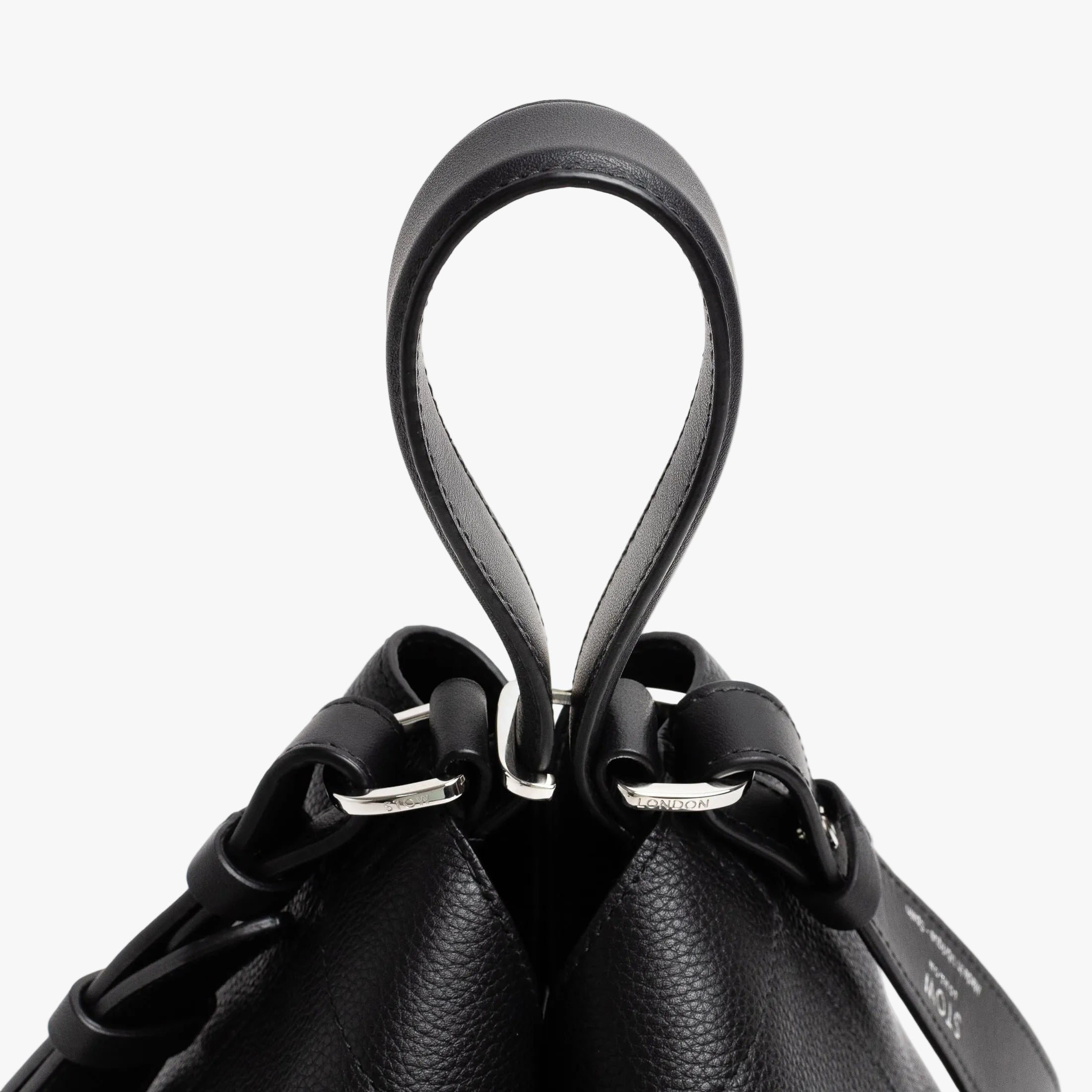Close up of the handles on Stow London's Curve bag in Black pebbled leather featuring silver stainless steel hardware and clip and detachable strap on a light grey background