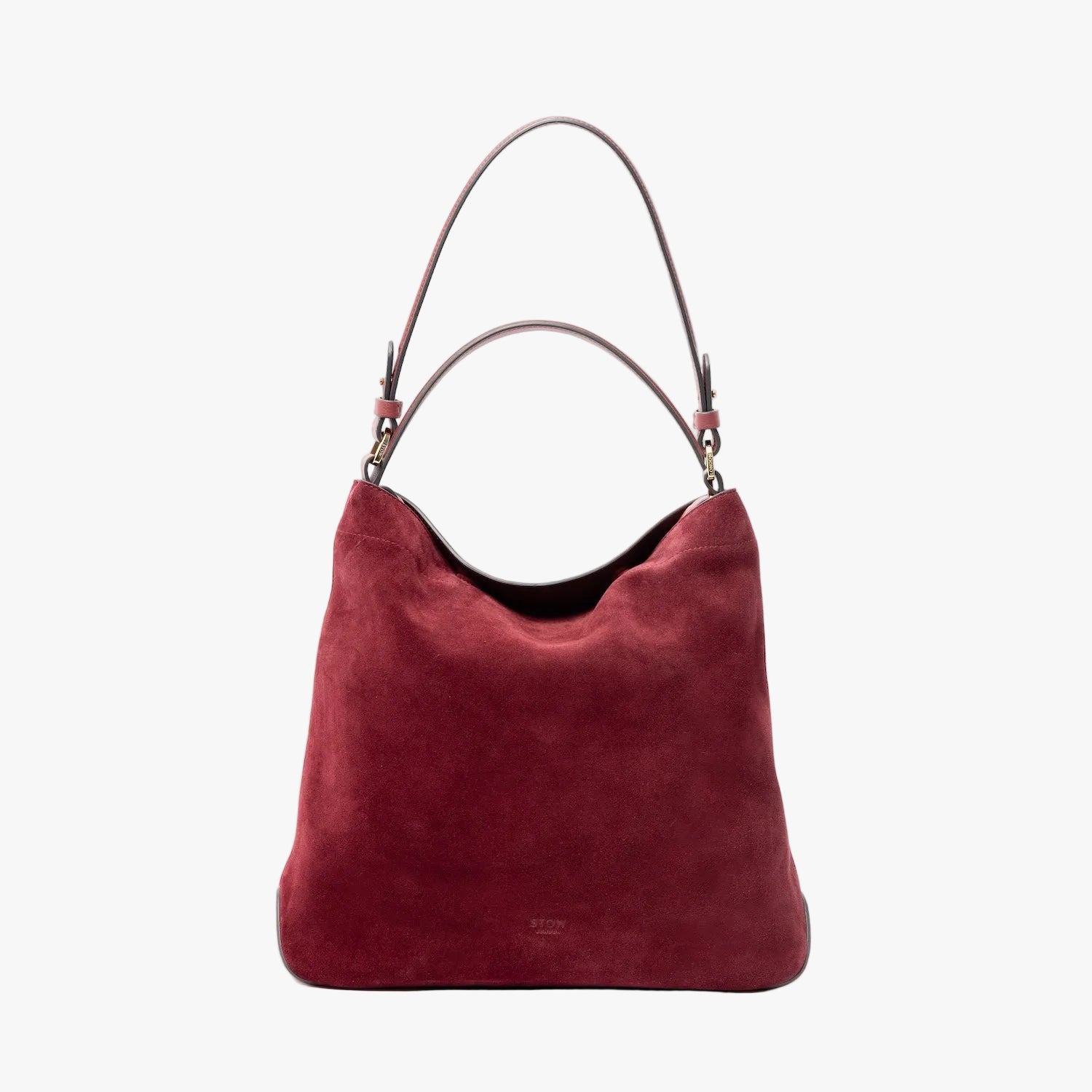 STOW London's Curve in Burgundy suede leather on a light grey background featuring the detachable shoulder strap and top handle with gold hardware