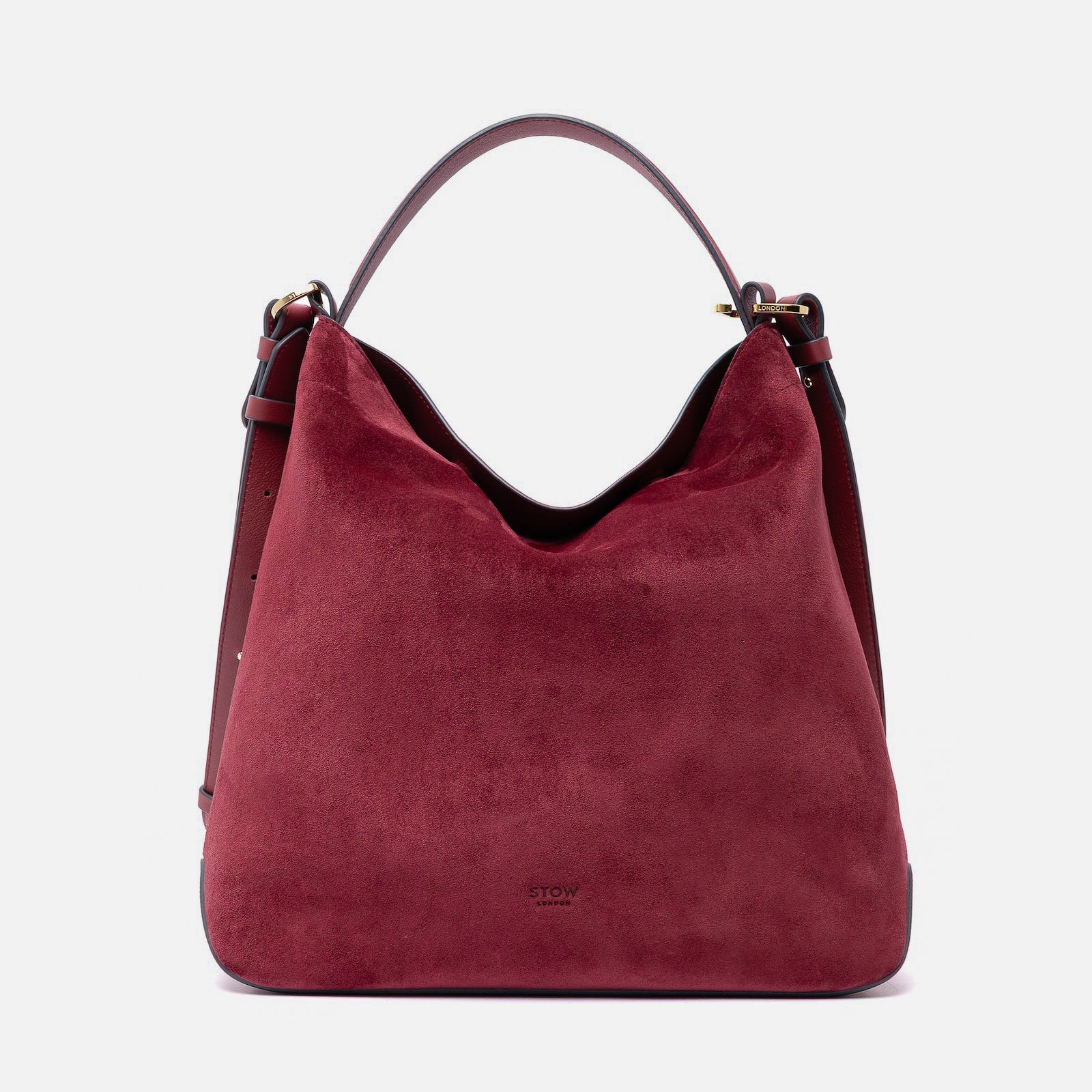 Stow London's Curve bag in Burgundy suede leather featuring gold-coated stainless steel hardware on a light grey background