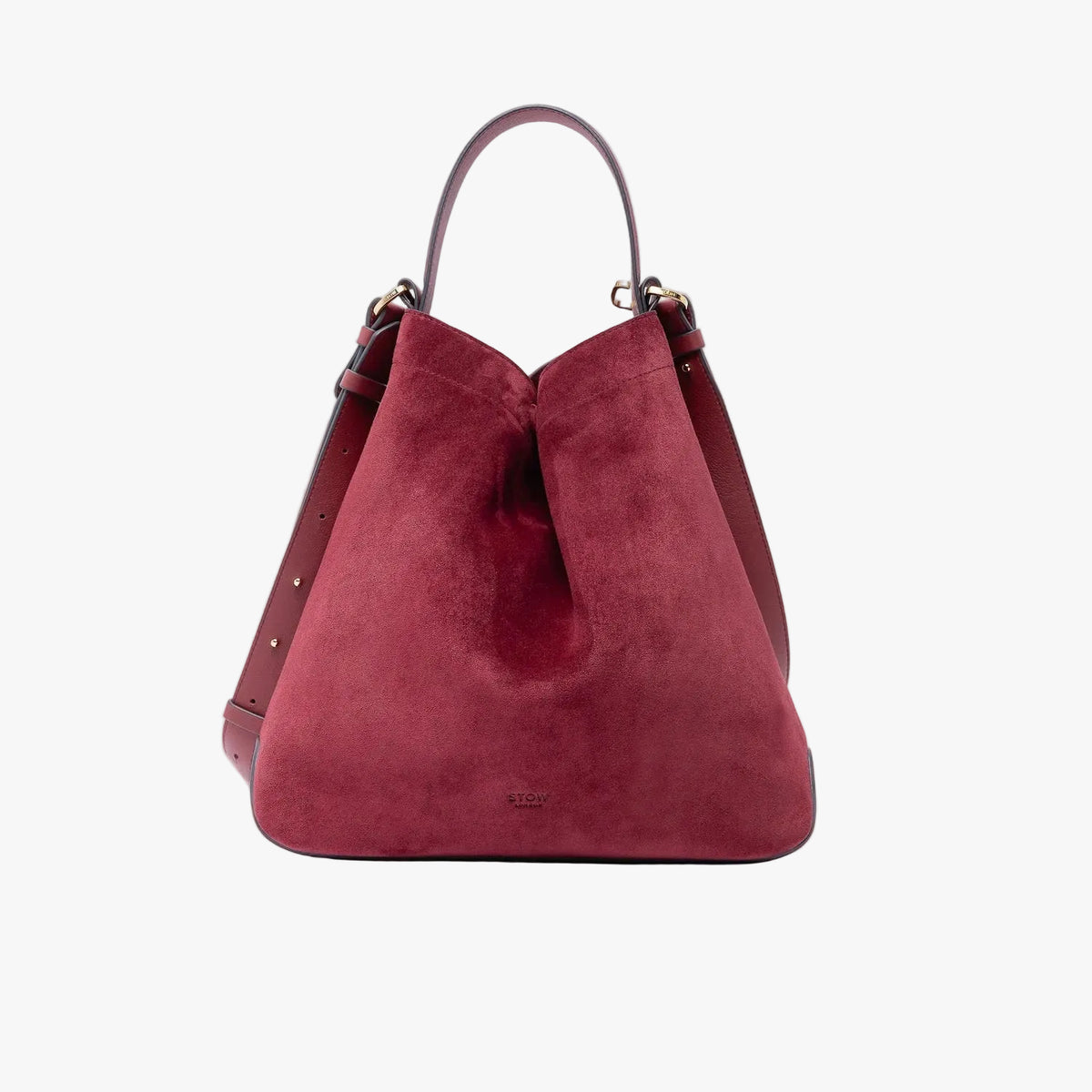 Stow London's Curve bag in Burgundy suede leather shaped in a triangular form featuring gold-coated stainless steel hardware on a light grey background