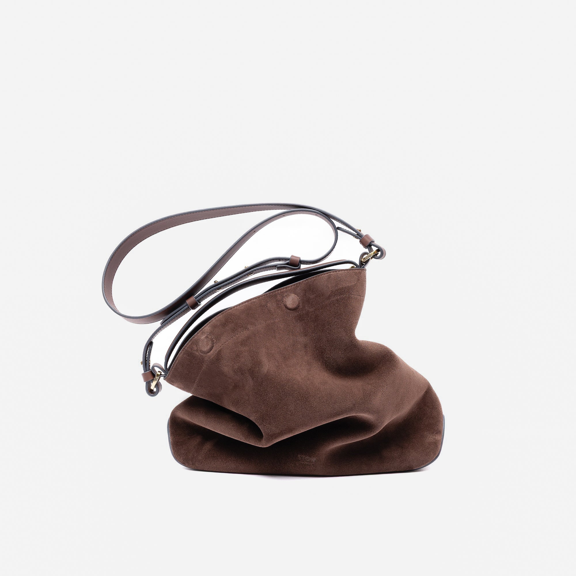 Stow London's Curve bag and detachable crossbody strap in Chocolate suede leather featuring gold-coated stainless steel hardware on a light grey background