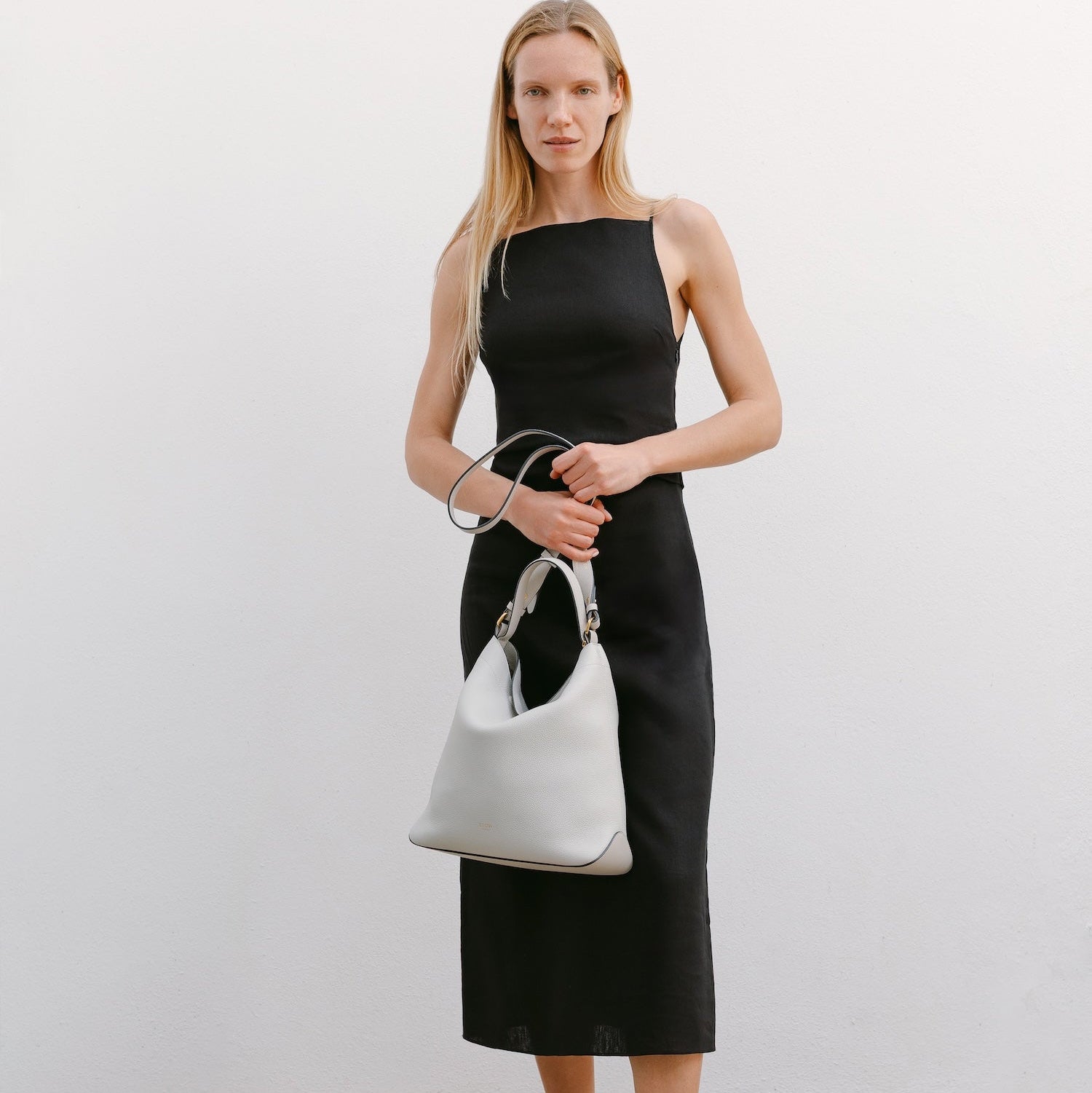 Model with STOW London's Curve bag in Cloud Grey pebbled leather featuring gold-coated stainless steel hardware