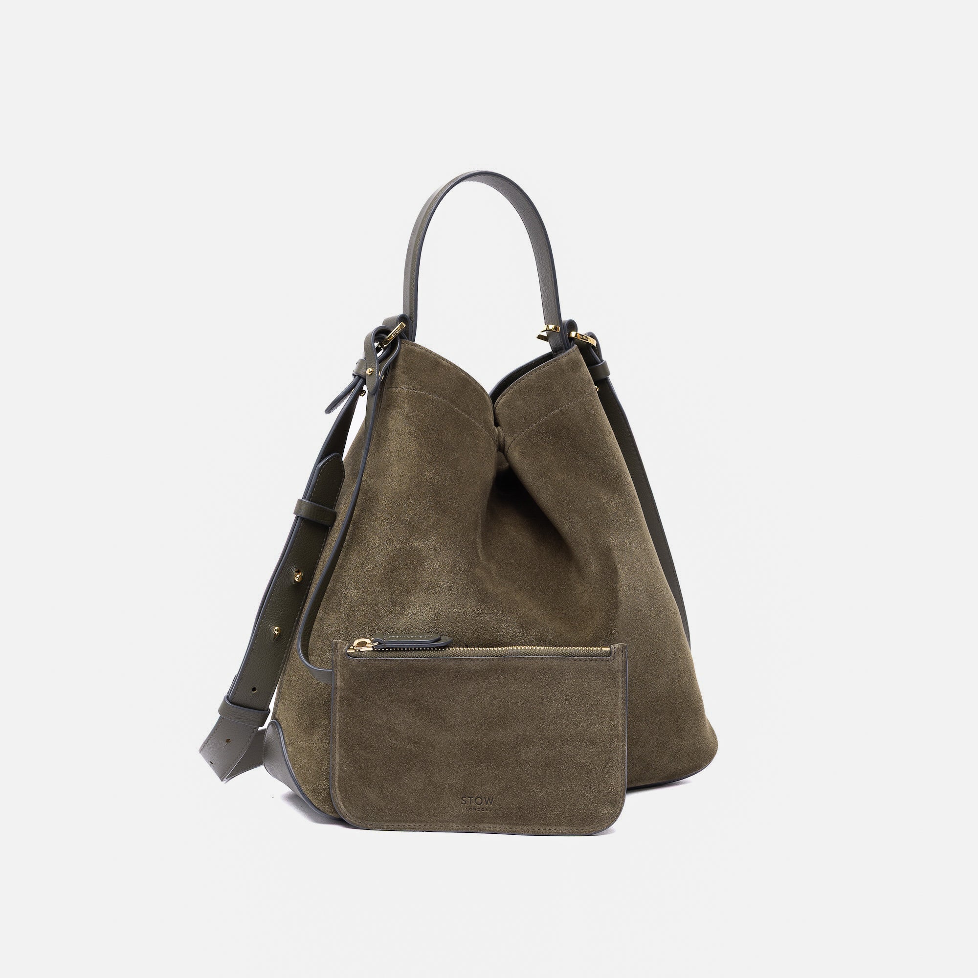 Stow London's Curve bag in Dark Green suede leather featuring its matching detachable interior pouch and gold-coated stainless steel hardware on a light grey background