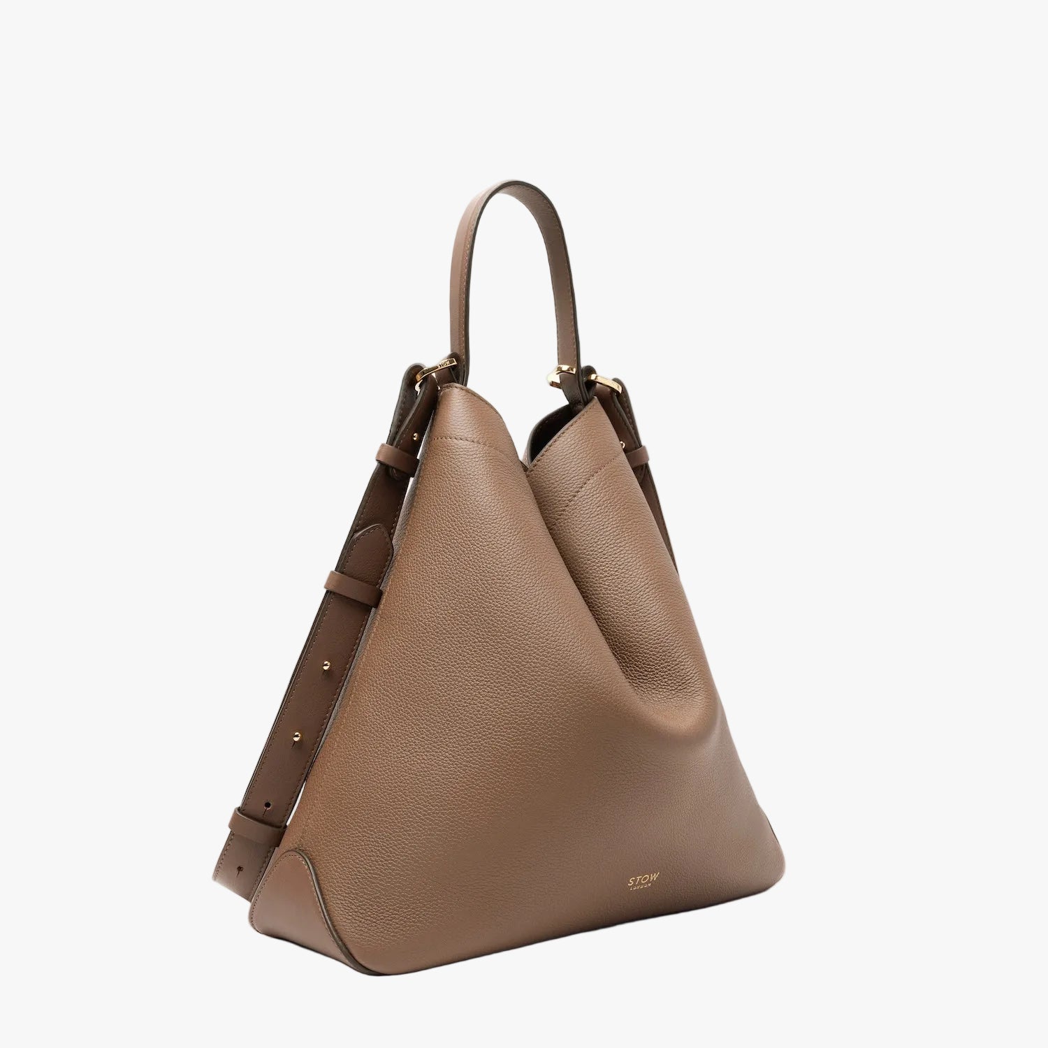 Off-axis view of STOW London's Curve bag in Mocha pebbled leather in its triangular form featuring gold-coated stainless steel hardware on a light grey background