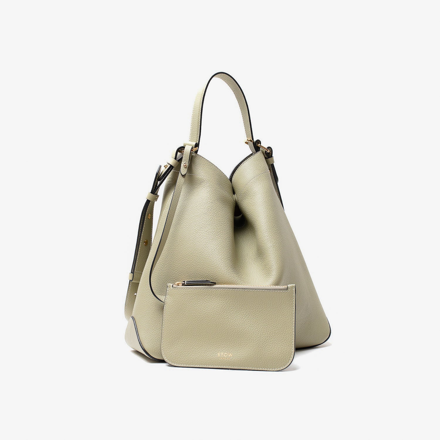Stow London's Curve bag in Pale Green pebbled leather and matching, detachable interior pouch featuring gold-coated stainless steel hardware on a light grey background