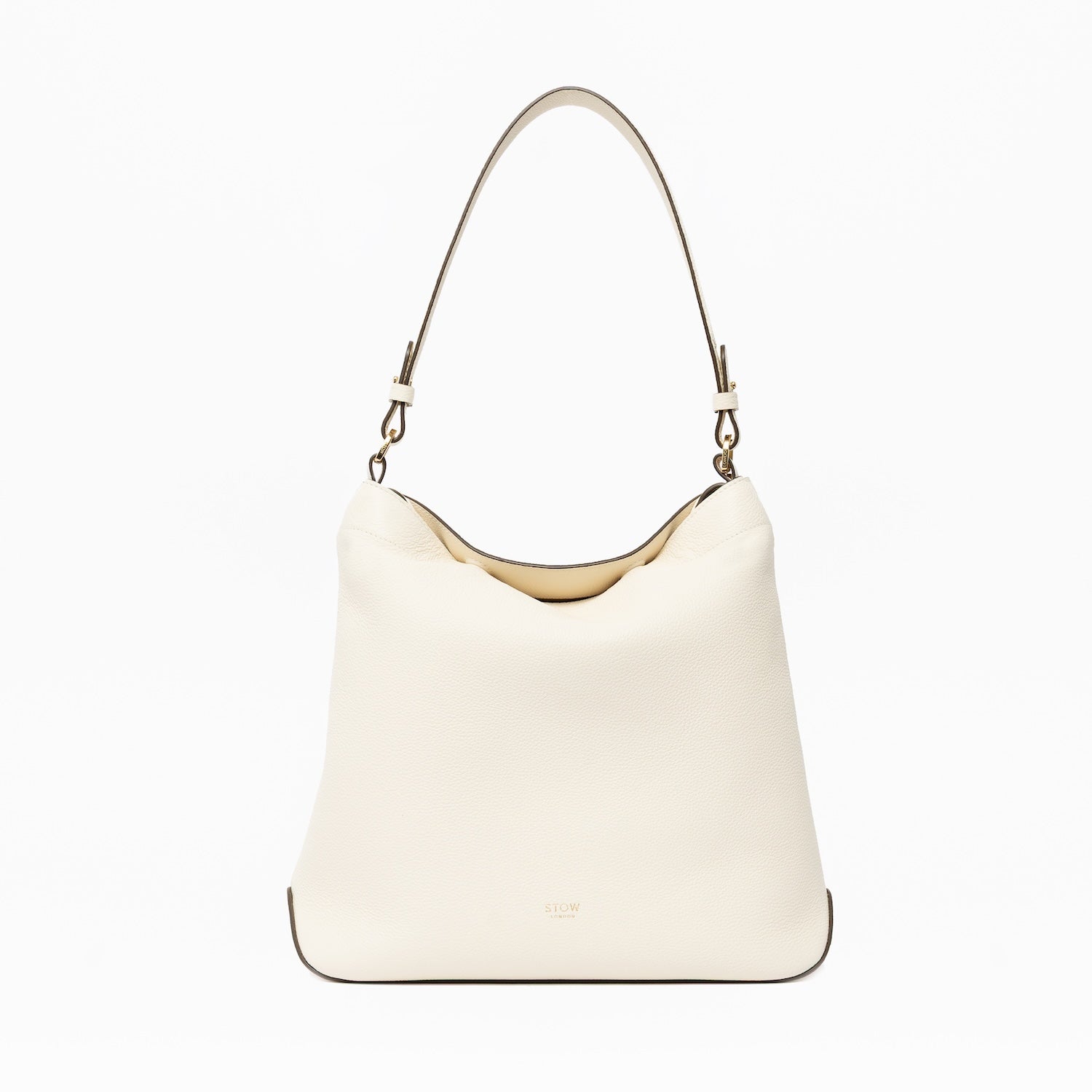 STOW London's Curve in Spring Moon leather on a light grey background featuring the detachable shoulder strap with gold hardware and details