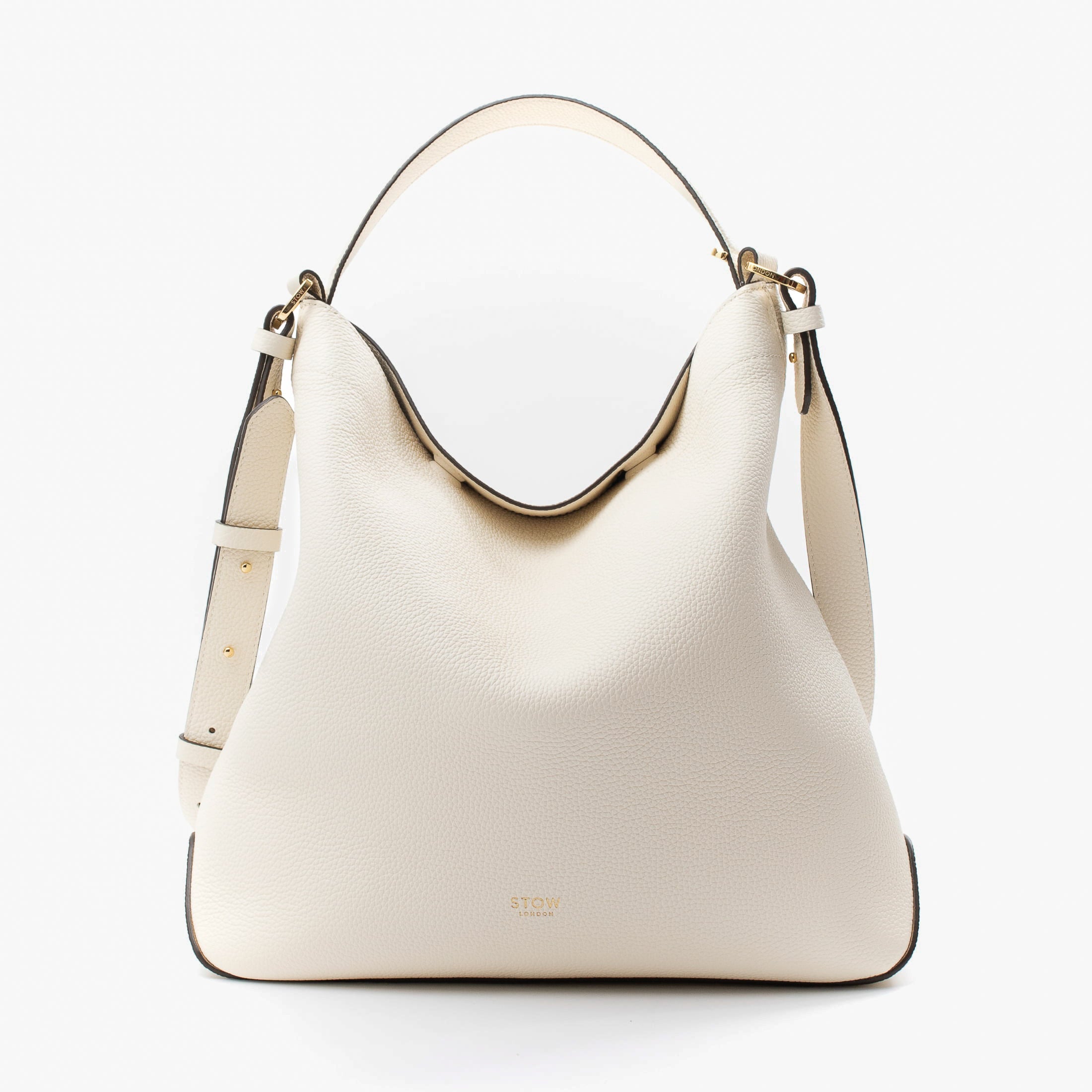 Stow London's Curve bag in Spring Moon pebbled leather featuring gold-coated stainless steel hardware on a light grey background