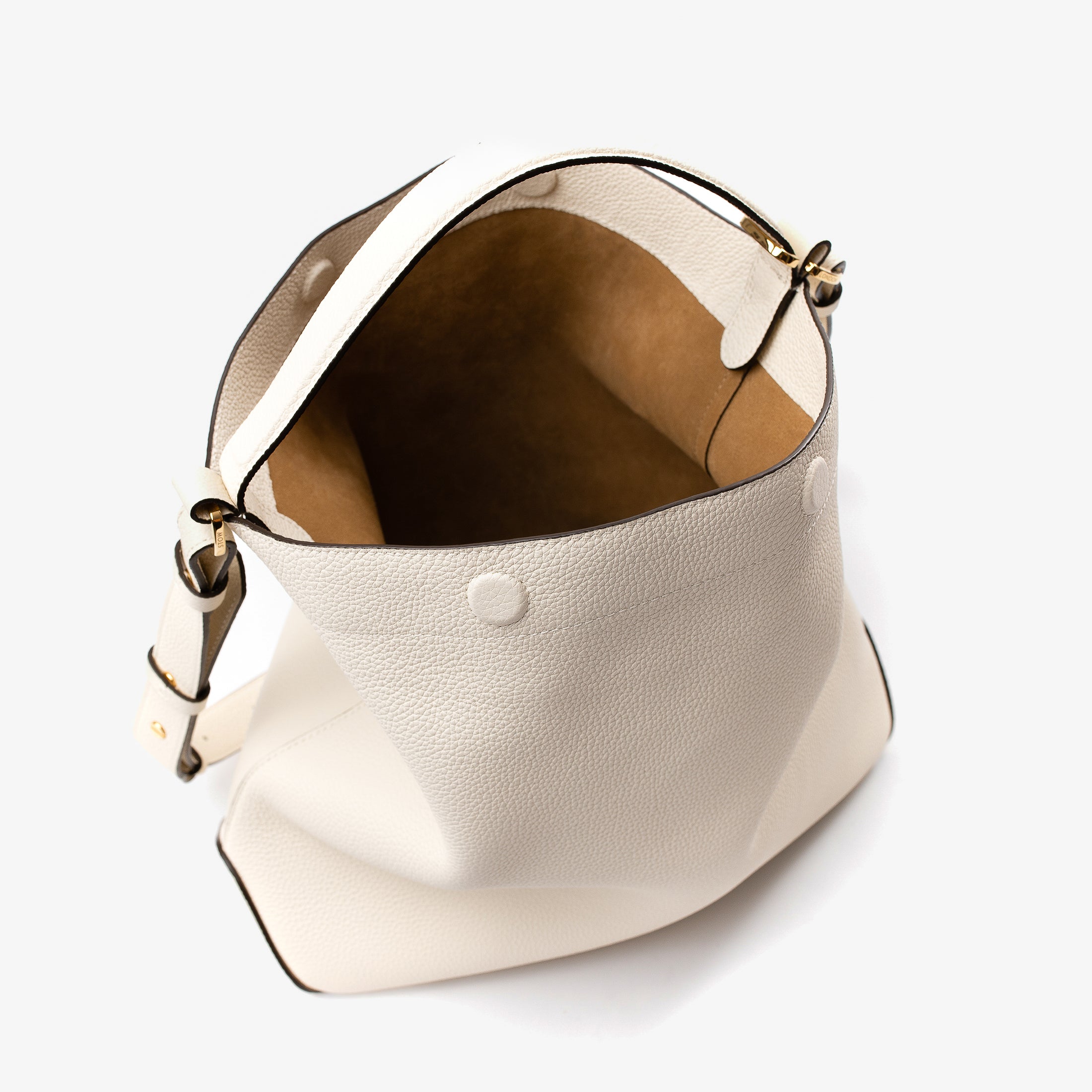 Top angle view ofStow London's Curve bag in Spring Moon pebbled leather showing the cognac suede interior lining ad hidden magnetic closures featuring gold-coated stainless steel hardware on a light grey background