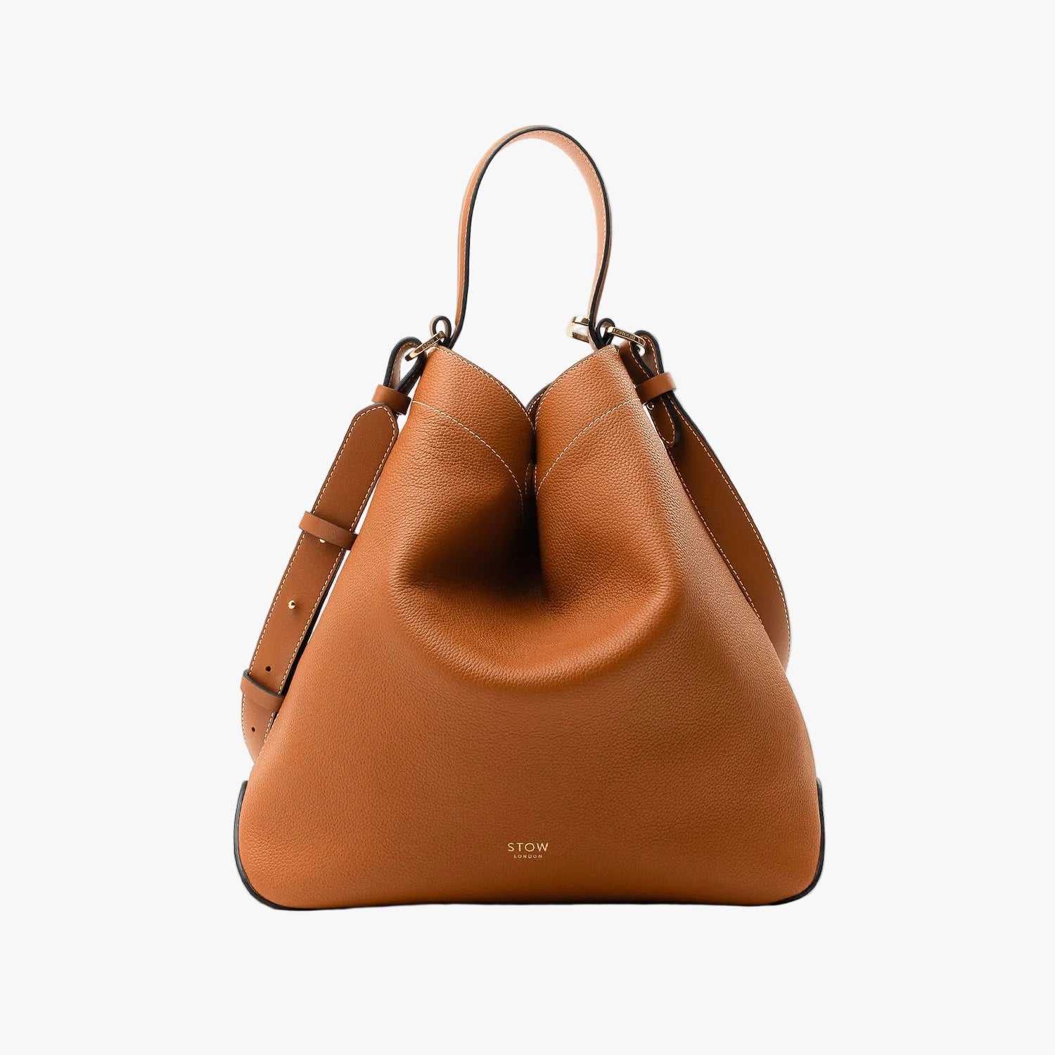 Stow London's Curve bag in Earth Tan pebbled leather in a triangular shape featuring gold-coated stainless steel hardware on a light grey background