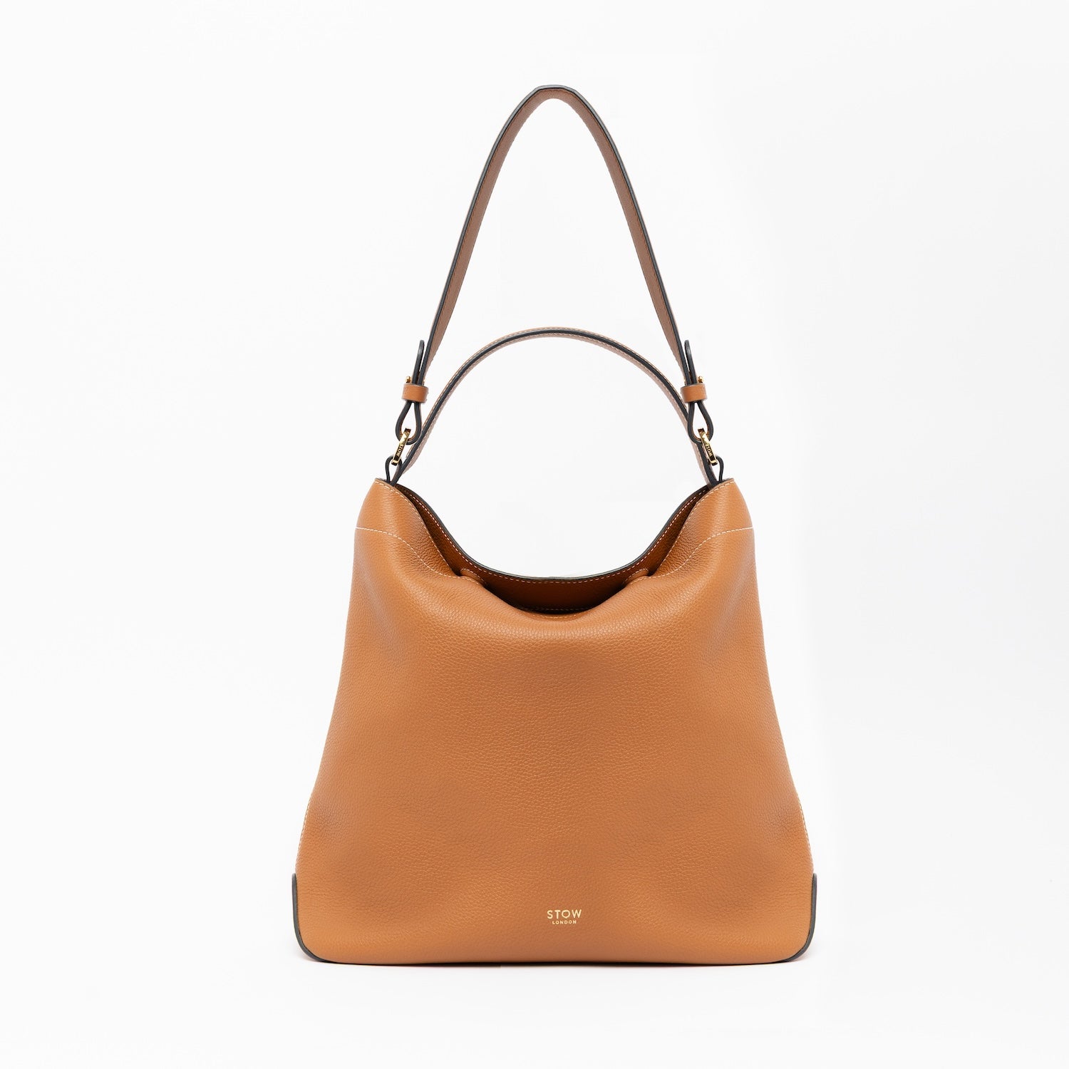 STOW London's Curve in Earth Tan leather on a light grey background featuring the detachable shoulder strap with gold hardware and details