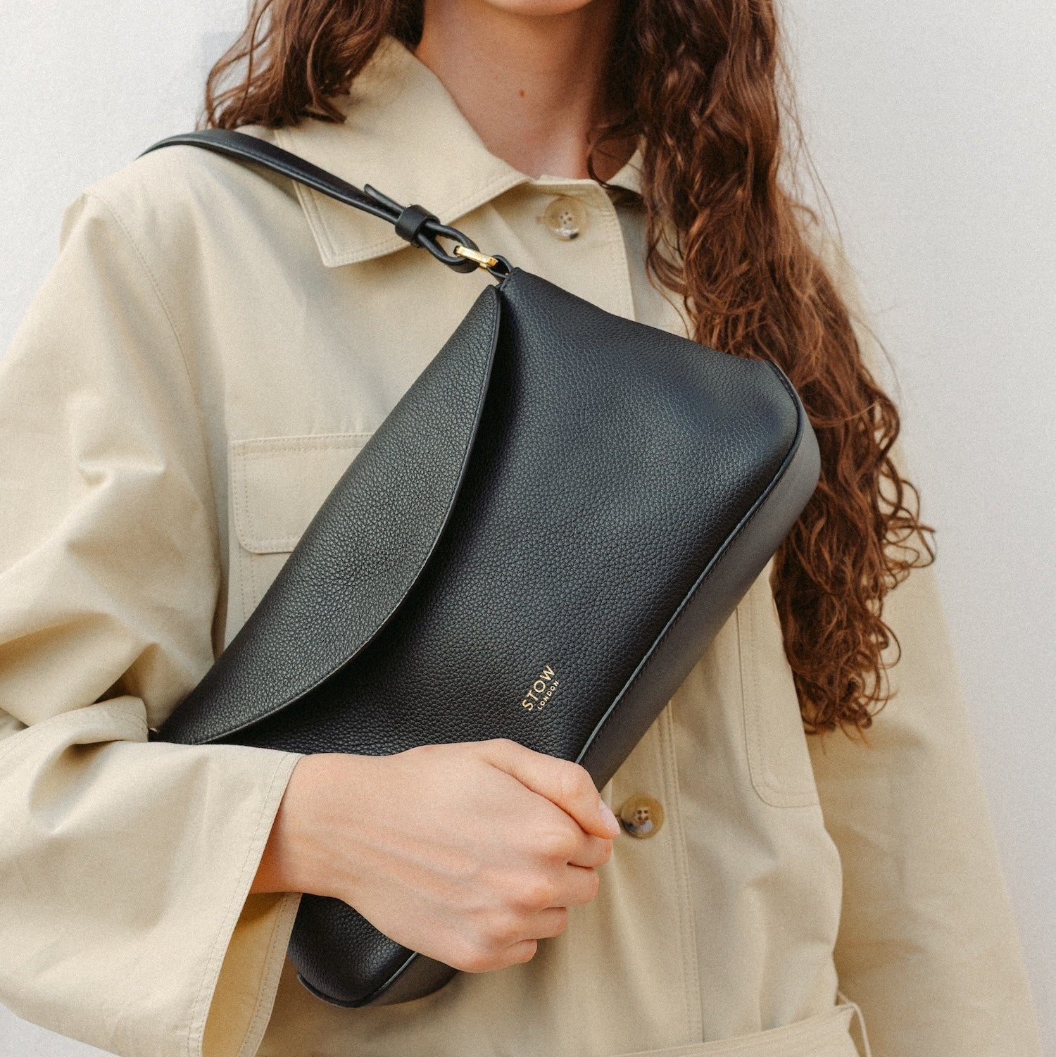 Model wearing STOW London's East West in Black leather featuring the detachable shoulder strap with gold hardware and details