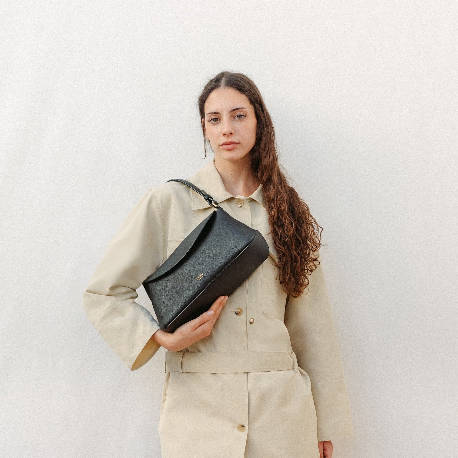 Model wearing STOW London's East West and detachable shoulder strap in Black leather featuring gold hardware and details