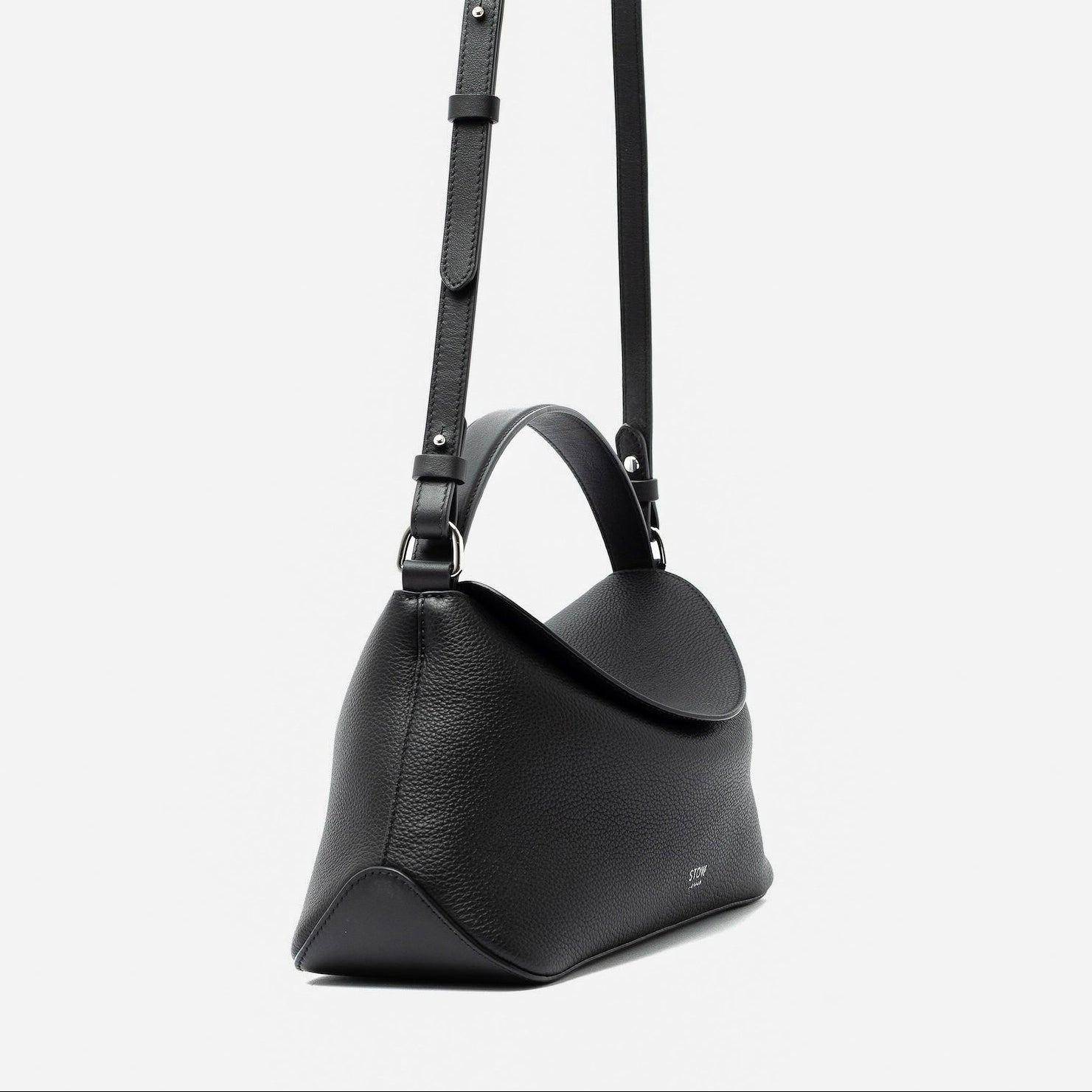 Side view of STOW London's East West and detachable crossbody strap in Black pebbled leather featuring silver stainless steel hardware on a light grey background