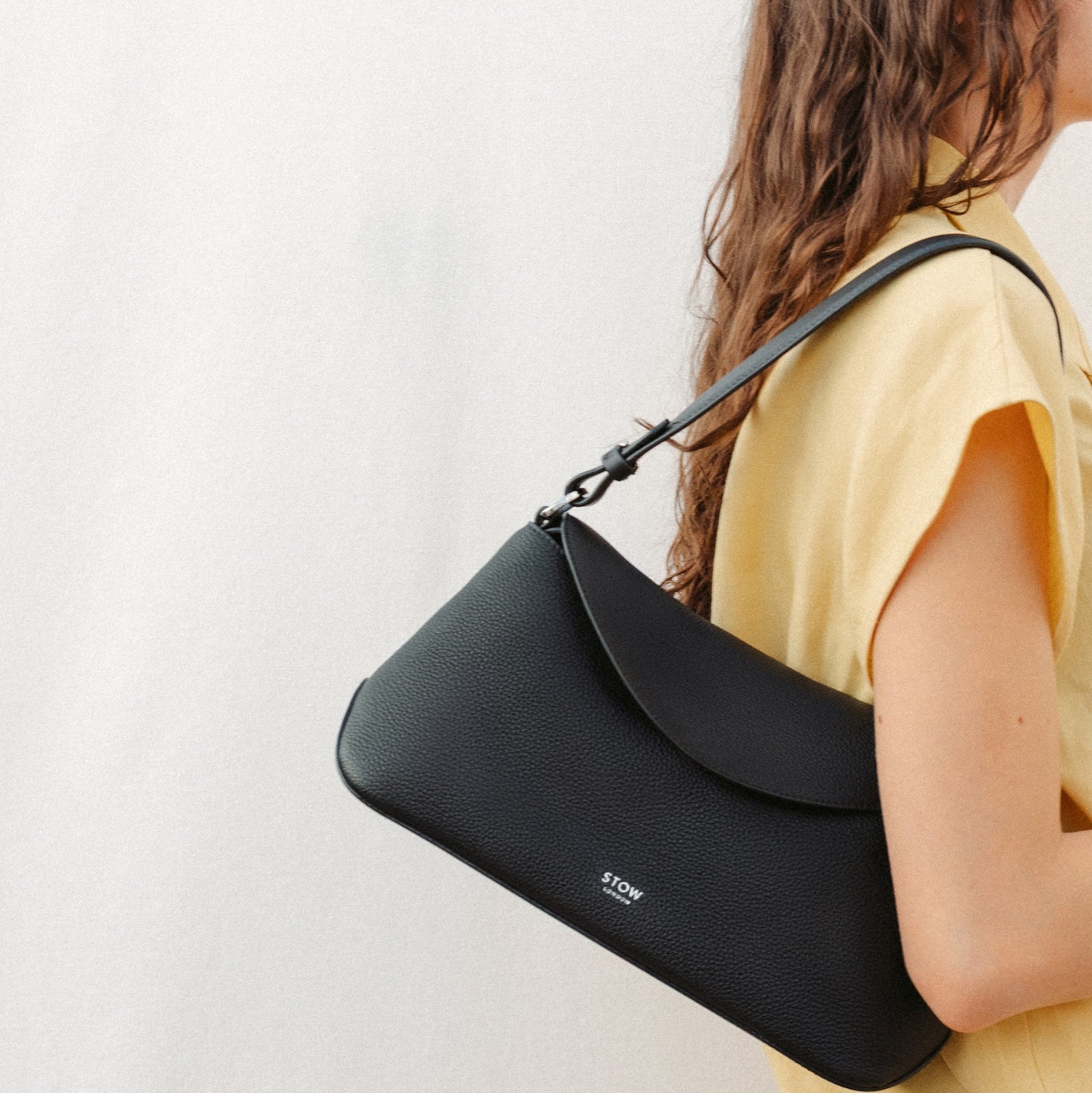 Model wearing STOW London's East West and detachable shoulder strap in Black leather featuring silver hardware and details