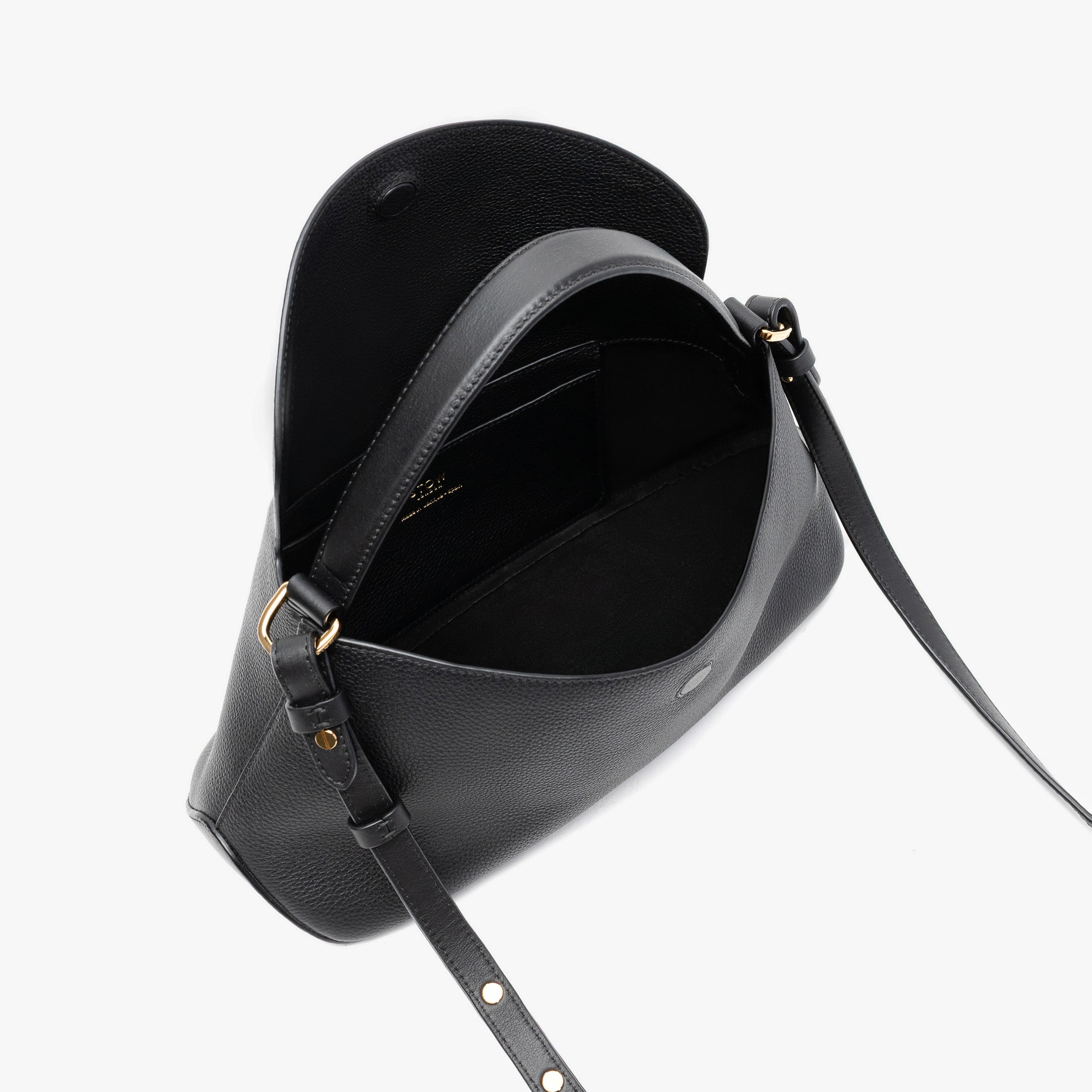 STOW London's East West in Black pebbled leather with flap open showing black suede interior and slip pocket featuring gold-coated stainless steel hardware on a light grey background