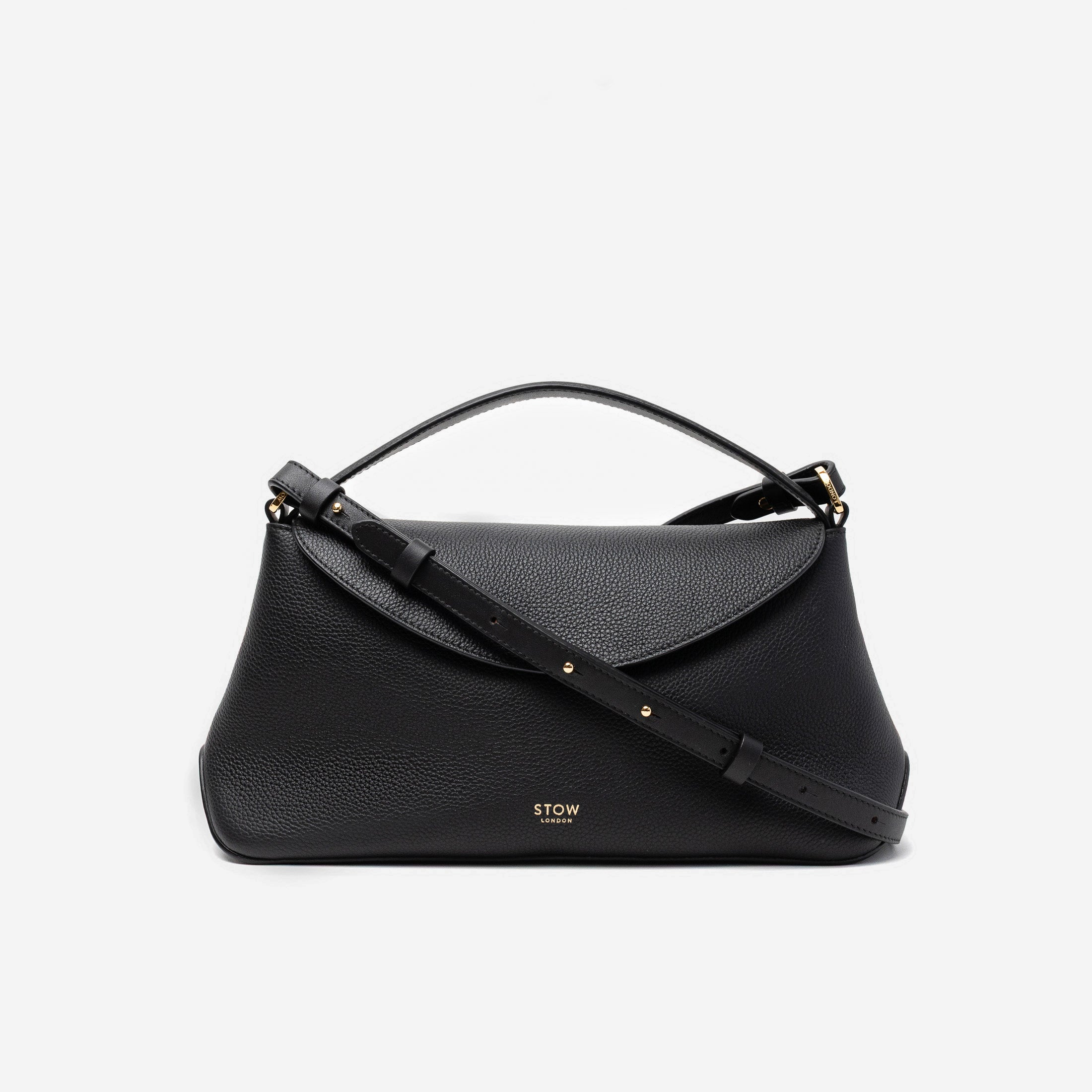 STOW London's East West in Black pebbled leather and detachable crossbody strap featuring gold-coated stainless steel hardware on a light grey background