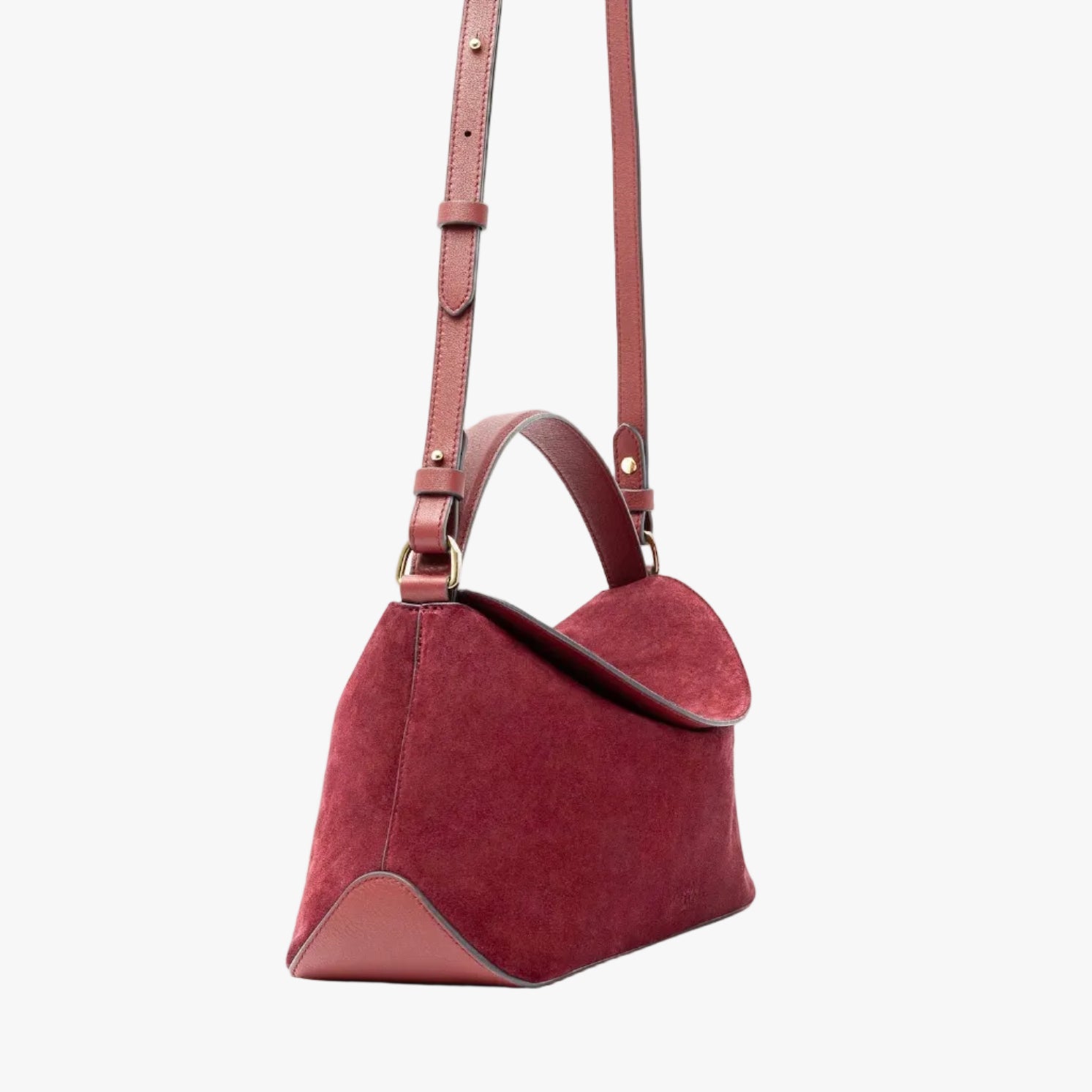 Off-axis view of STOW London's East West in Burgundy suede leather and detachable crossbody strap featuring gold-coated stainless steel hardware on a light grey background