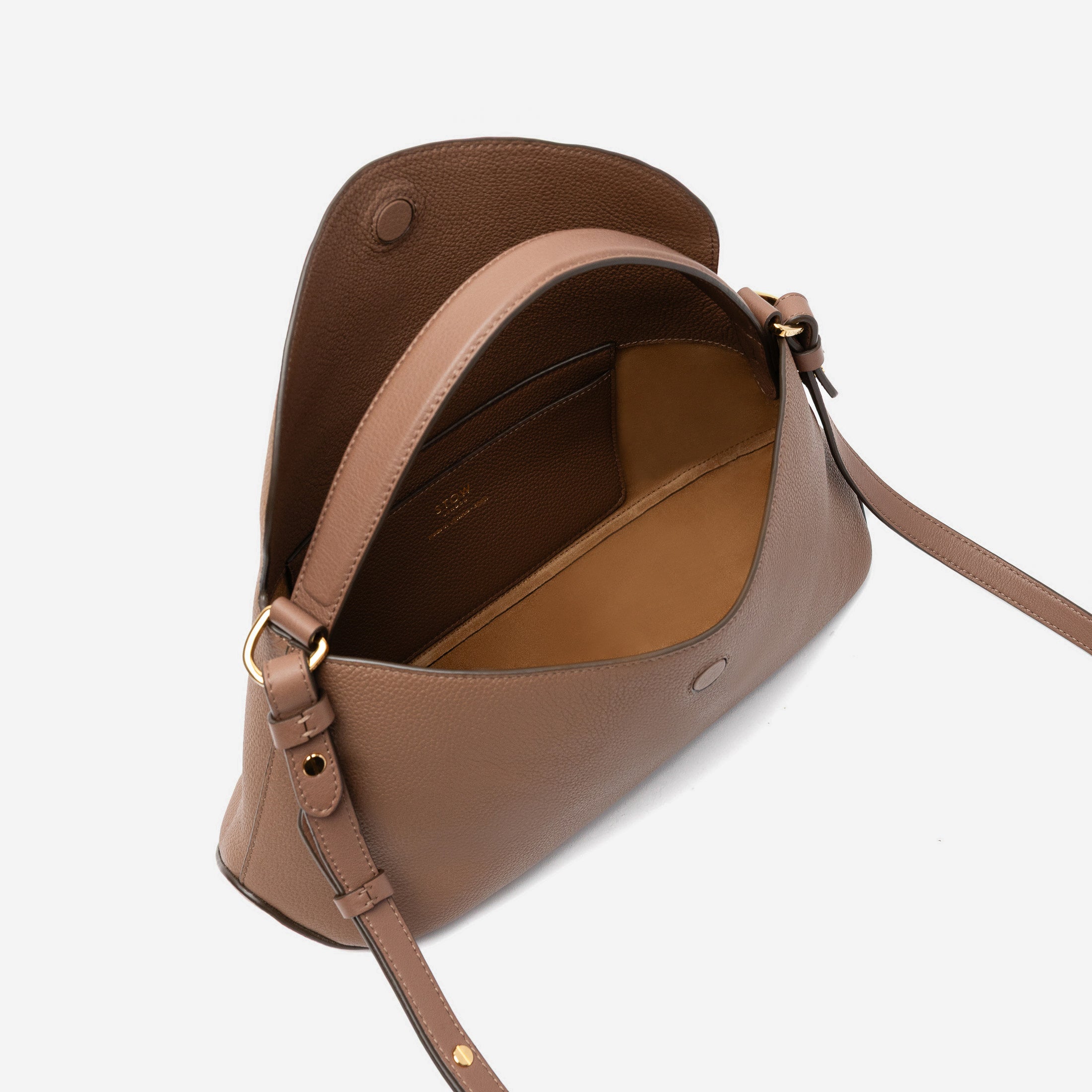 STOW London's East West in Mocha pebbled leather with flap open showing suede interior and slip pocket featuring gold-coated stainless steel hardware on a light grey background