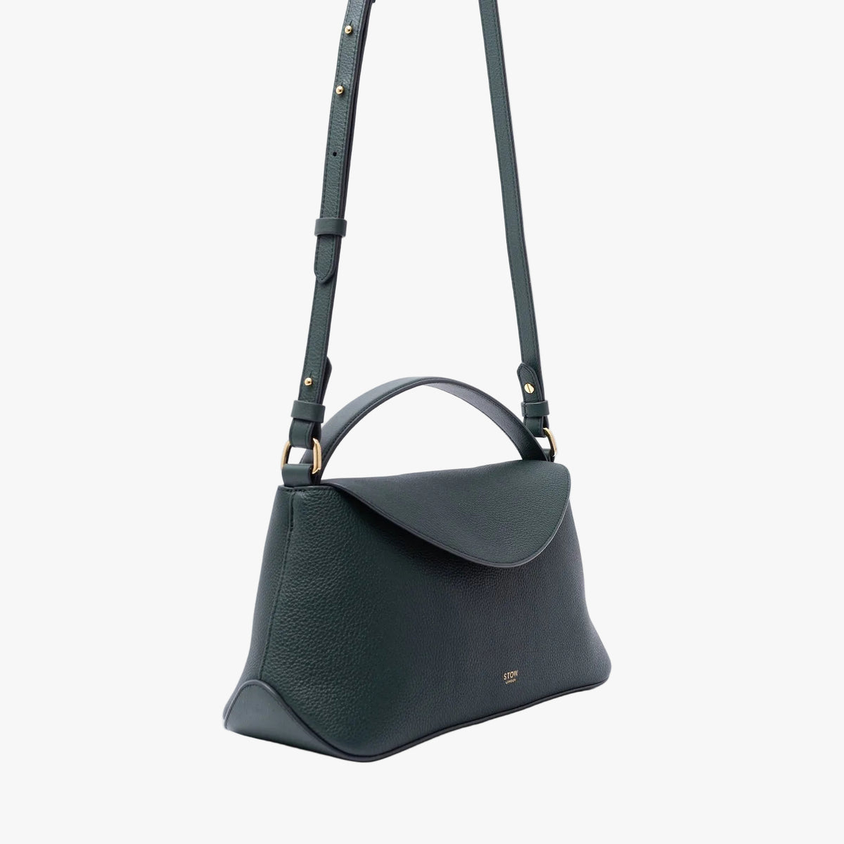 Off-axis view of STOW London's East West in New Forest pebbled leather on a light grey background featuring gold-coated stainless steel hardware and the detachable crossbody strap