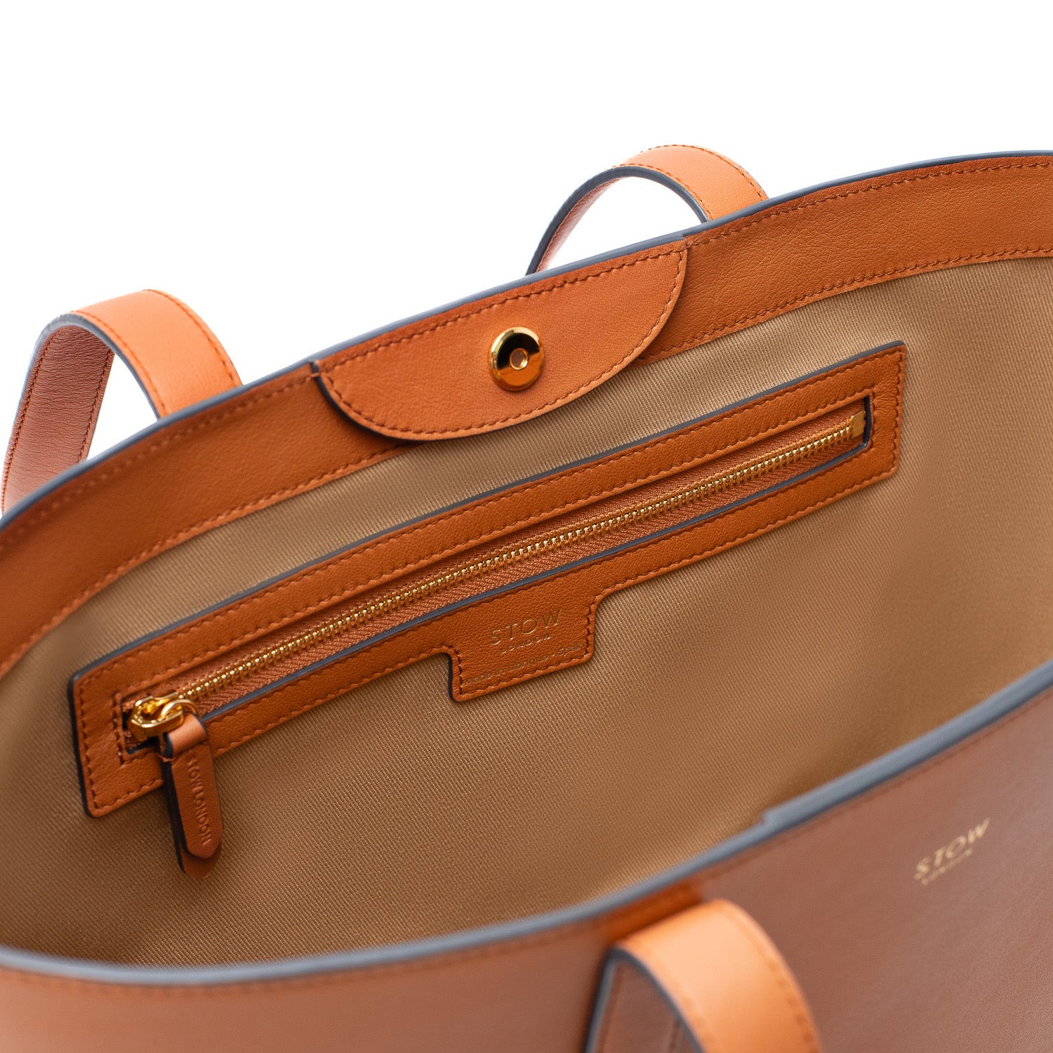 Close up of STOW London's Everyday Tote bag in Earth Tan showing interior cotton lining and zip pocket featuring gold-coated hardware on a white background