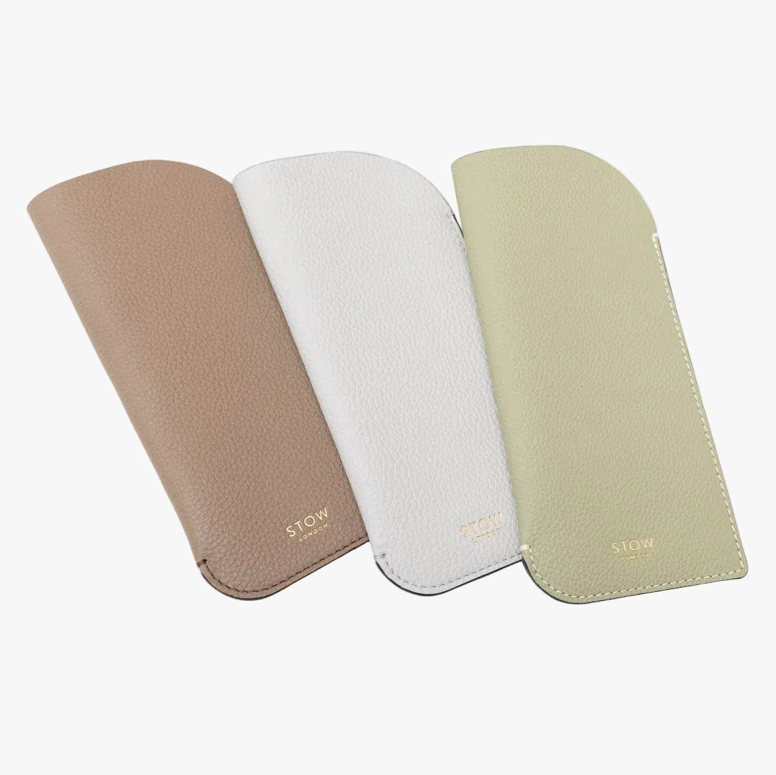 Shot of all three pebbled leather colours of STOW London's Glasses Case featuring gold logos on a white background