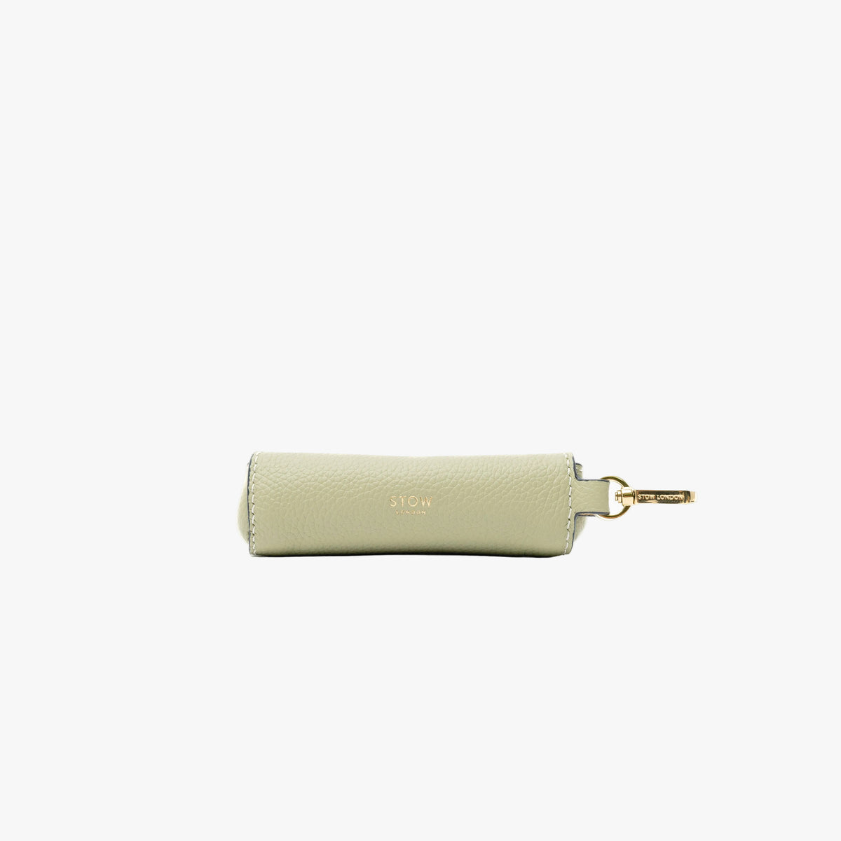 Back panel of STOW London's Lipstick Case in Pale Green pebbled leather featuring a gold-coated stainless steel clip and small embossed logo on a light grey background