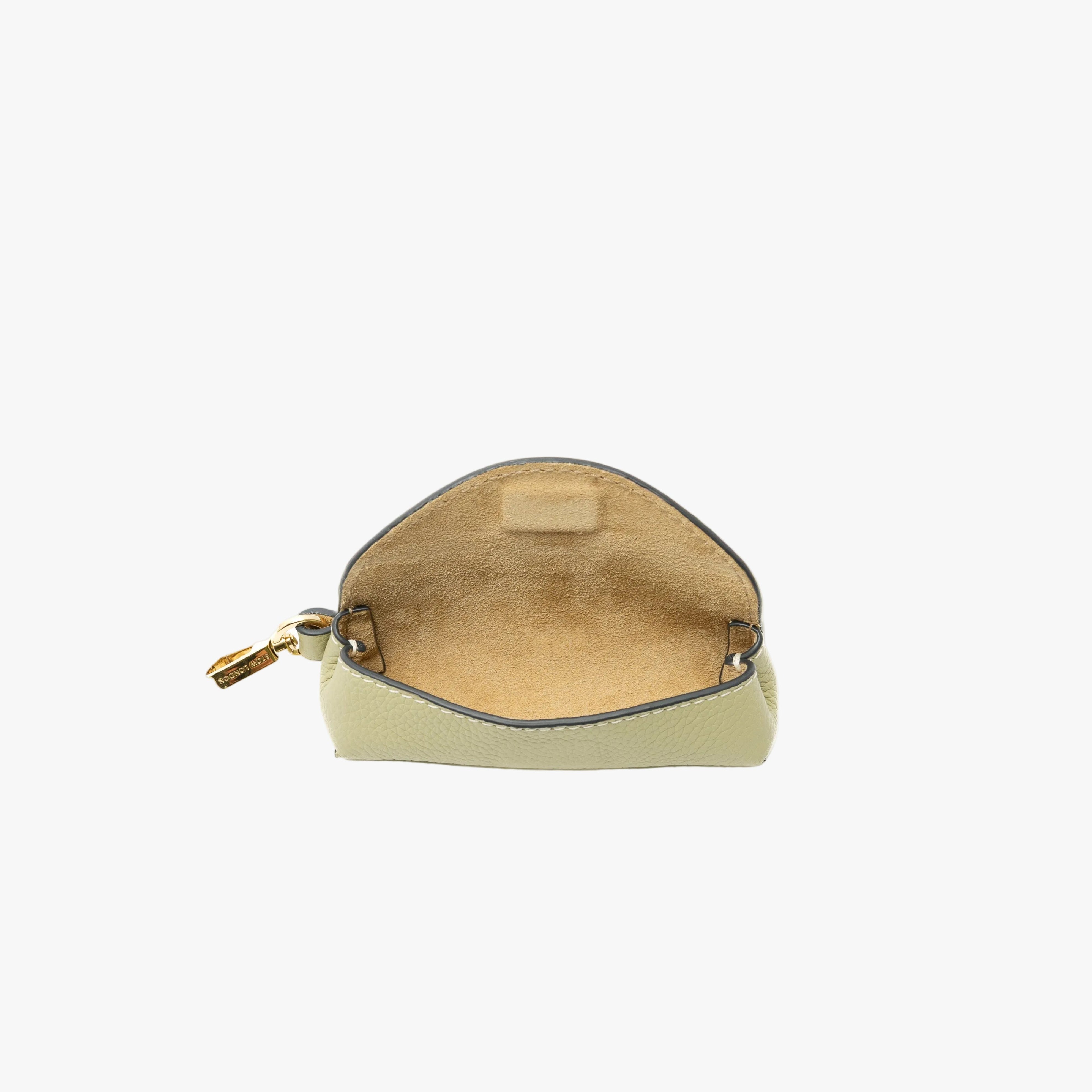 STOW London's Lipstick Case in Pale Green pebbled leather with flap open showing the beige suede interior featuring a gold-coated stainless steel clip on a light grey background