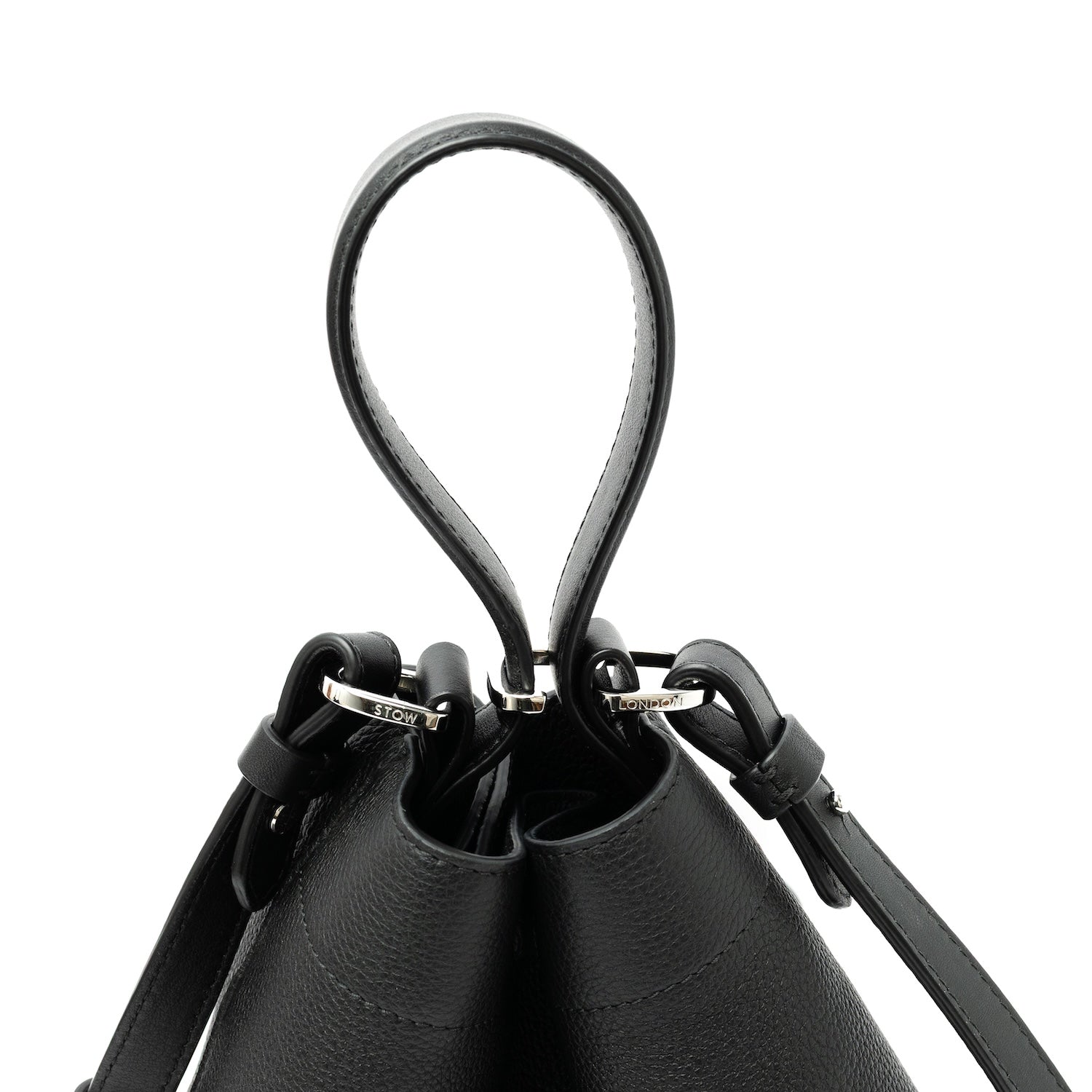 Close up view of the top handle, clip and detachable strap on STOW London's Midi Curve bag in Black pebbled and smooth leather featuring silver stainless steel hardware on a white background